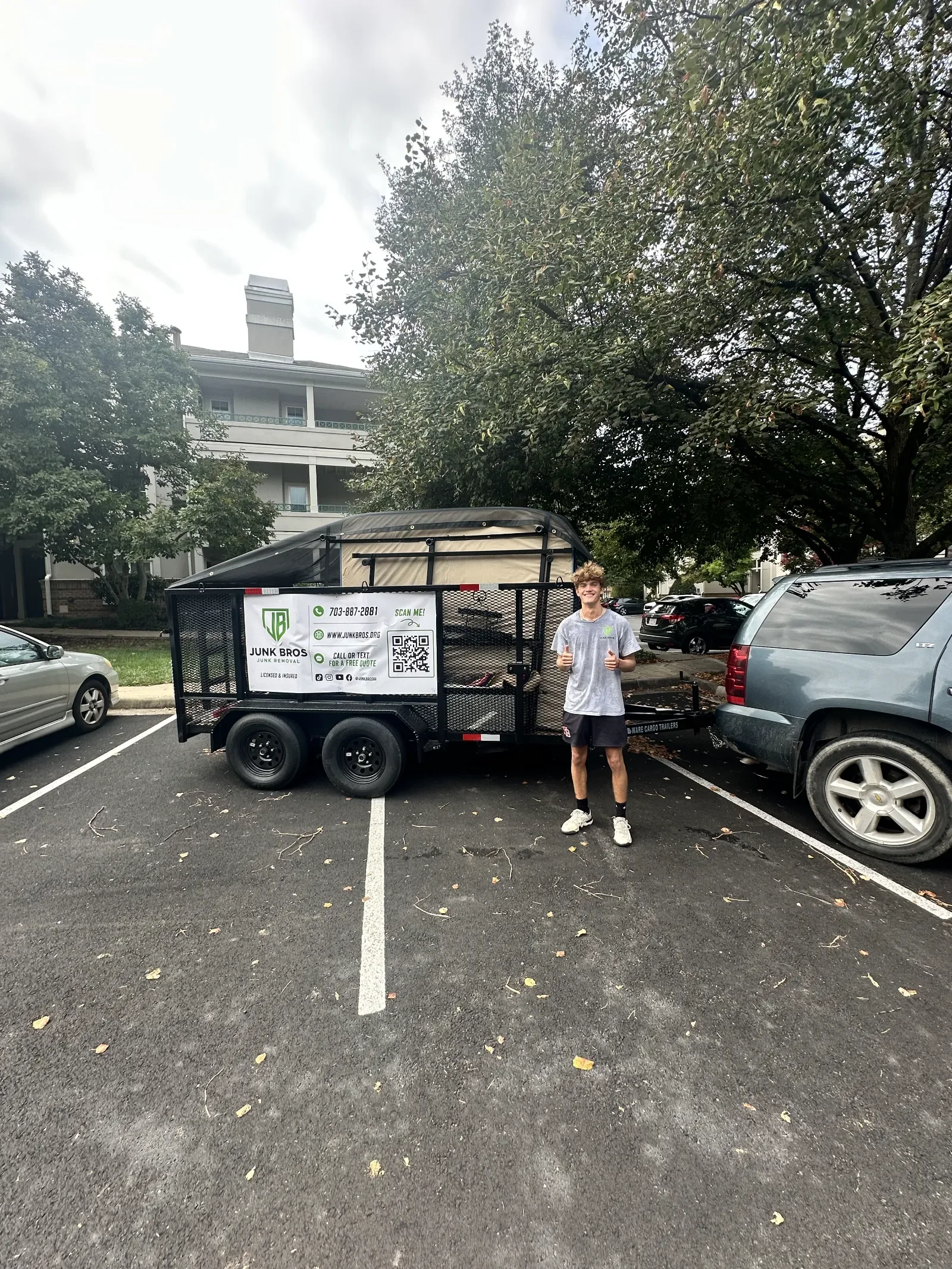 Junk Bros crew member with a loaded junk removal trailer at an apartment complex in Prince William County, VA