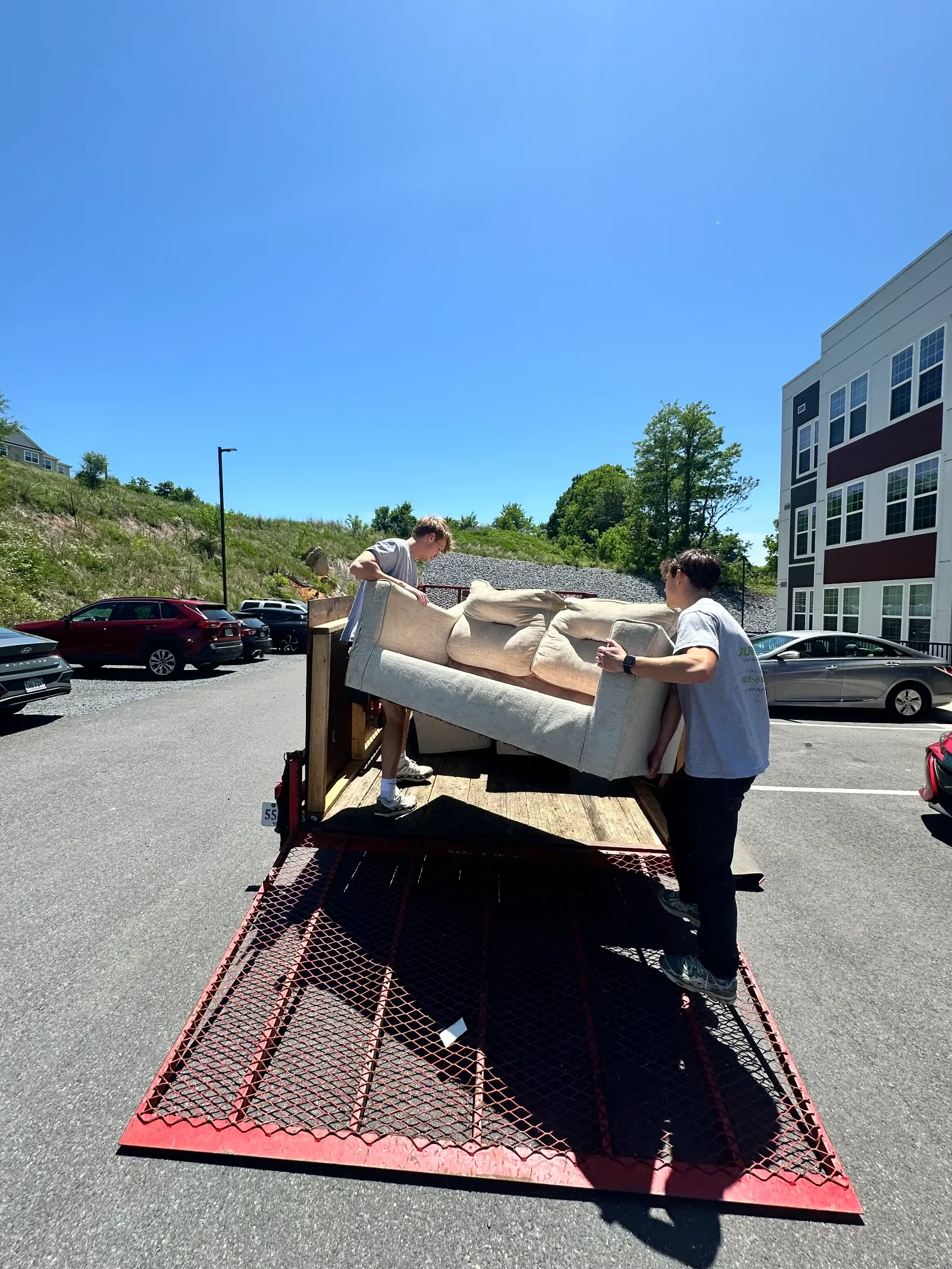 Junk Bros crew lifting a couch into a trailer during a furniture removal job