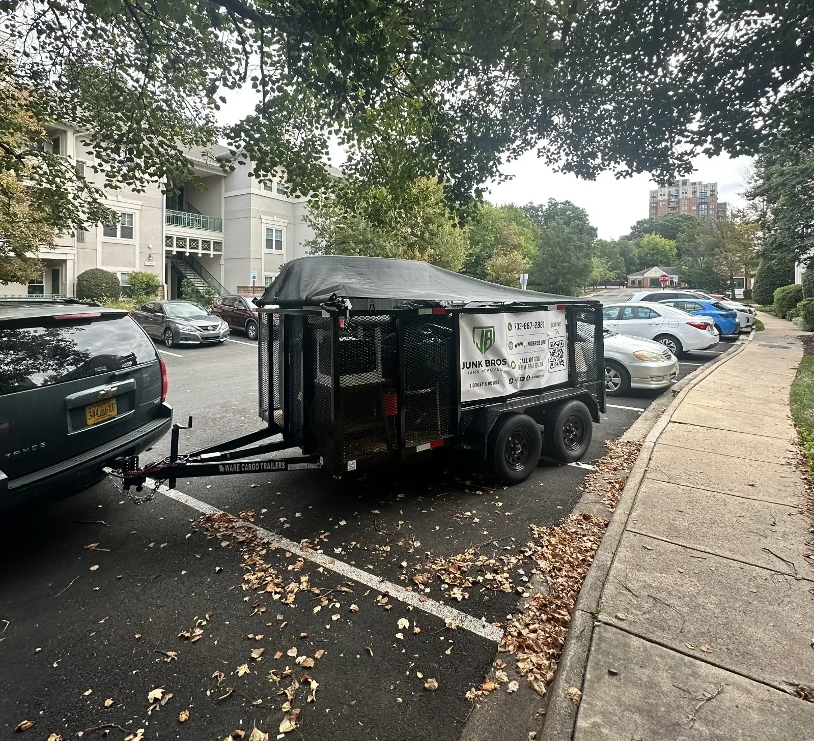 Tarped Junk Bros trailer full of junk parked at an apartment community after a cleanout