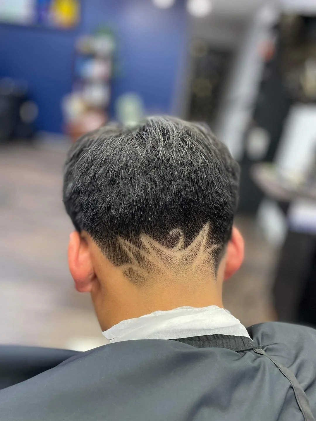Back of a man's head with a new haircut featuring a wave design shaved into the fade.