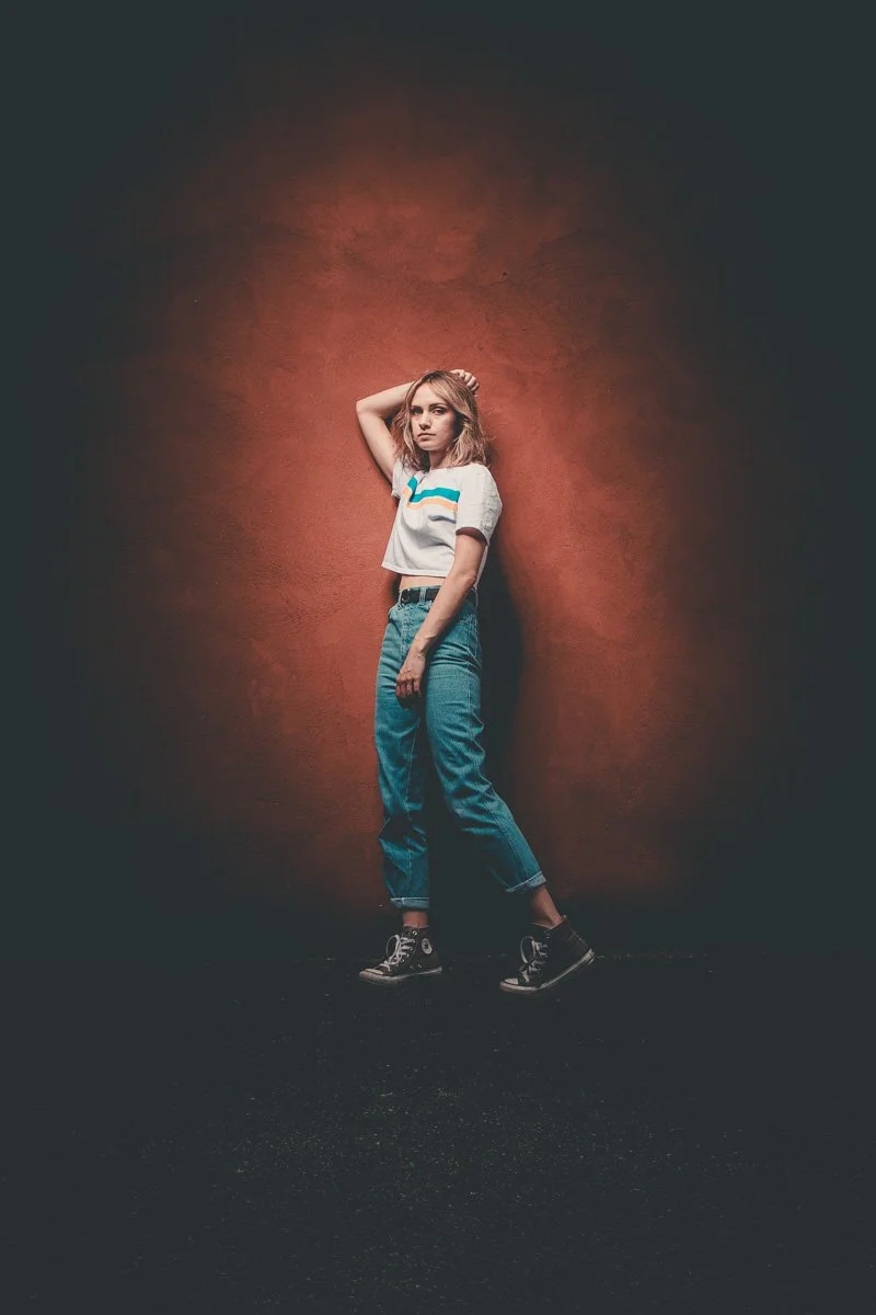 lady posing for the camera leaning against stucco wall