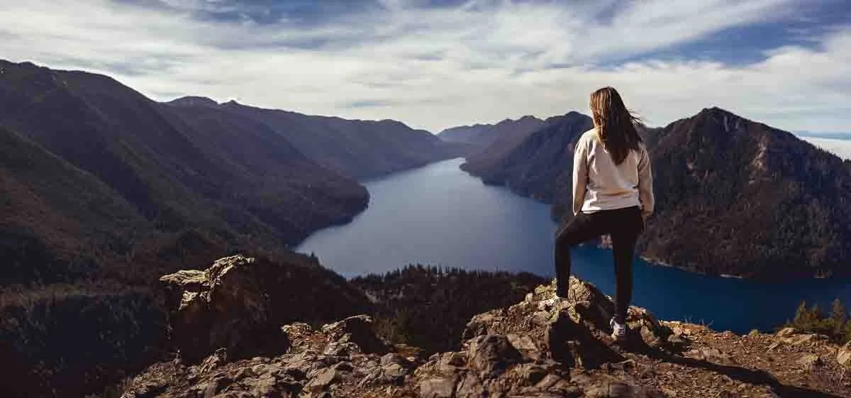 woman standing on a mountain overlooking a river
