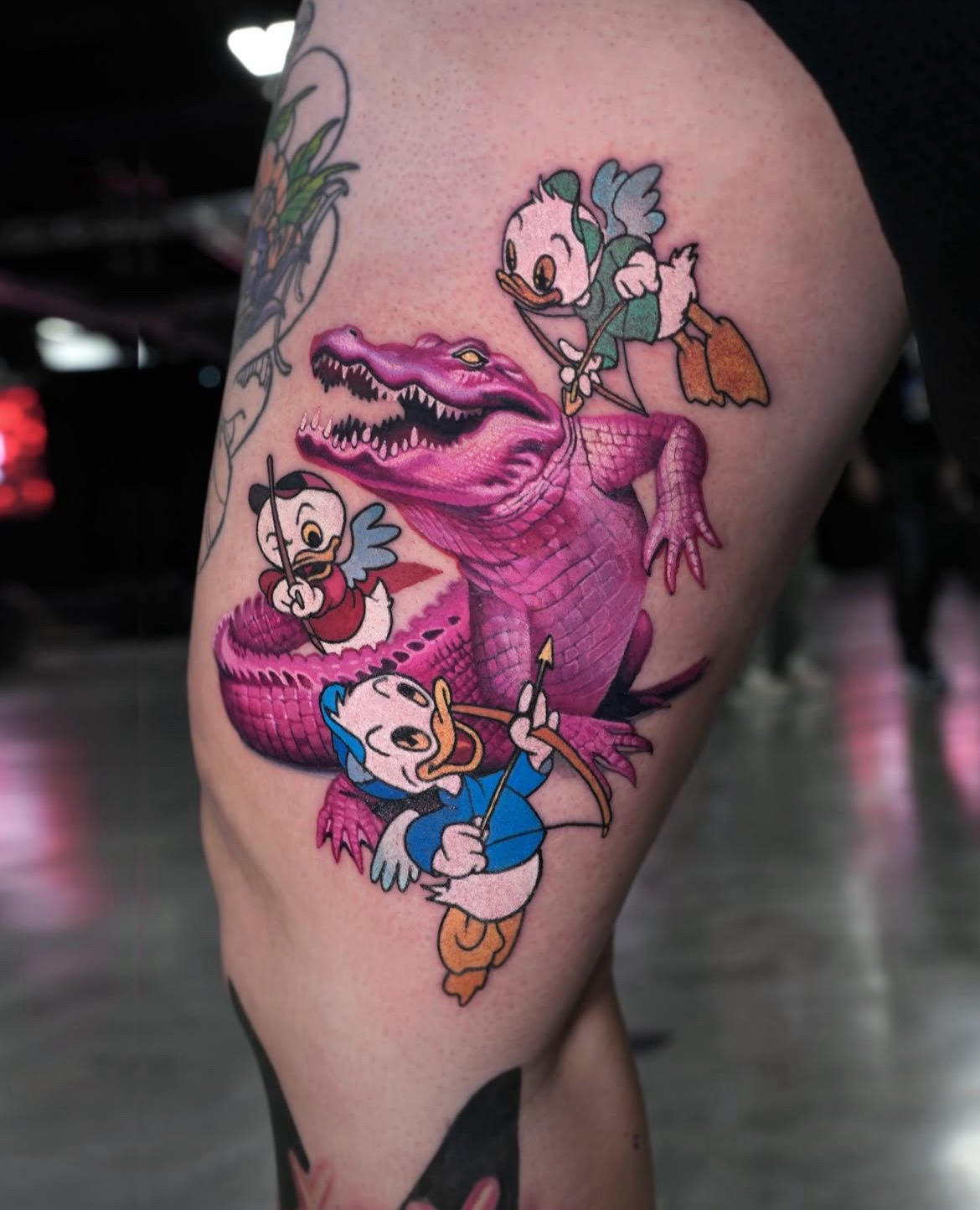 Tattoo featuring Disney's Donald Duck characters riding on a pink crocodile with an open mouth showing sharp teeth.