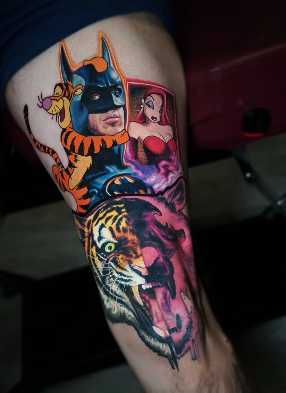 Colorful tattoo sleeve featuring cartoon characters, a superhero face with a mask, a female character with red hair, a roaring tiger, and a snarling wolf.