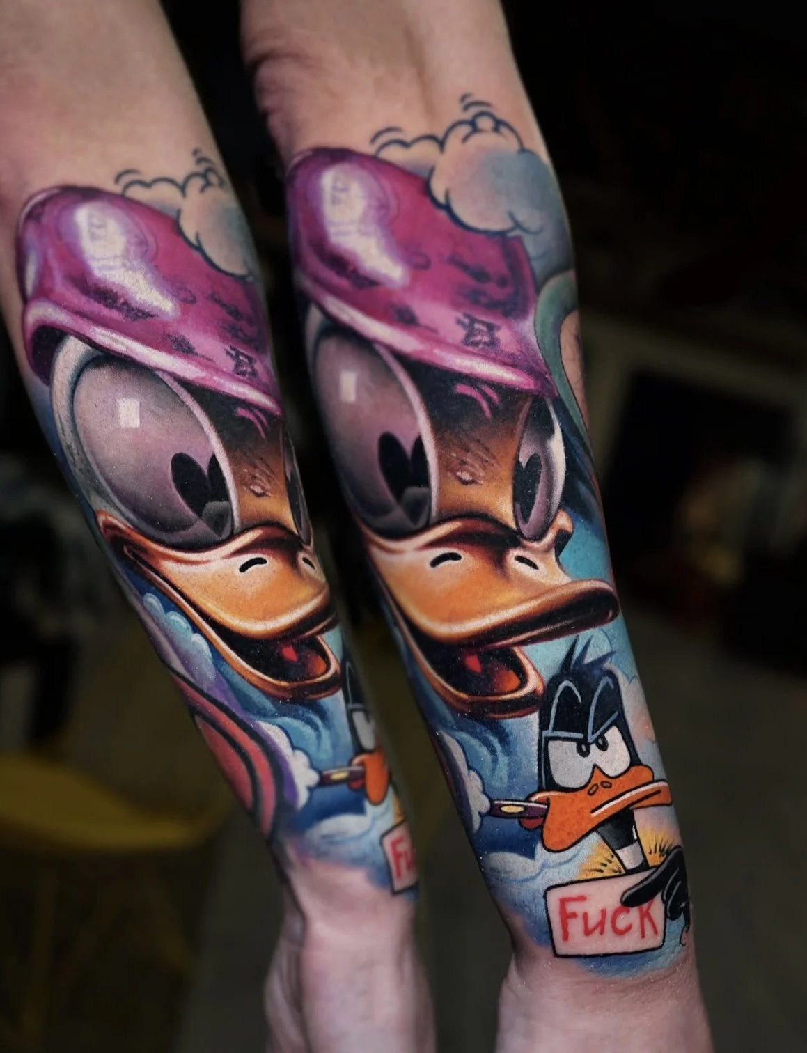 Colorful tattoo of Disney characters Mickey Mouse, Donald Duck, and Daisy Duck on person's arm.