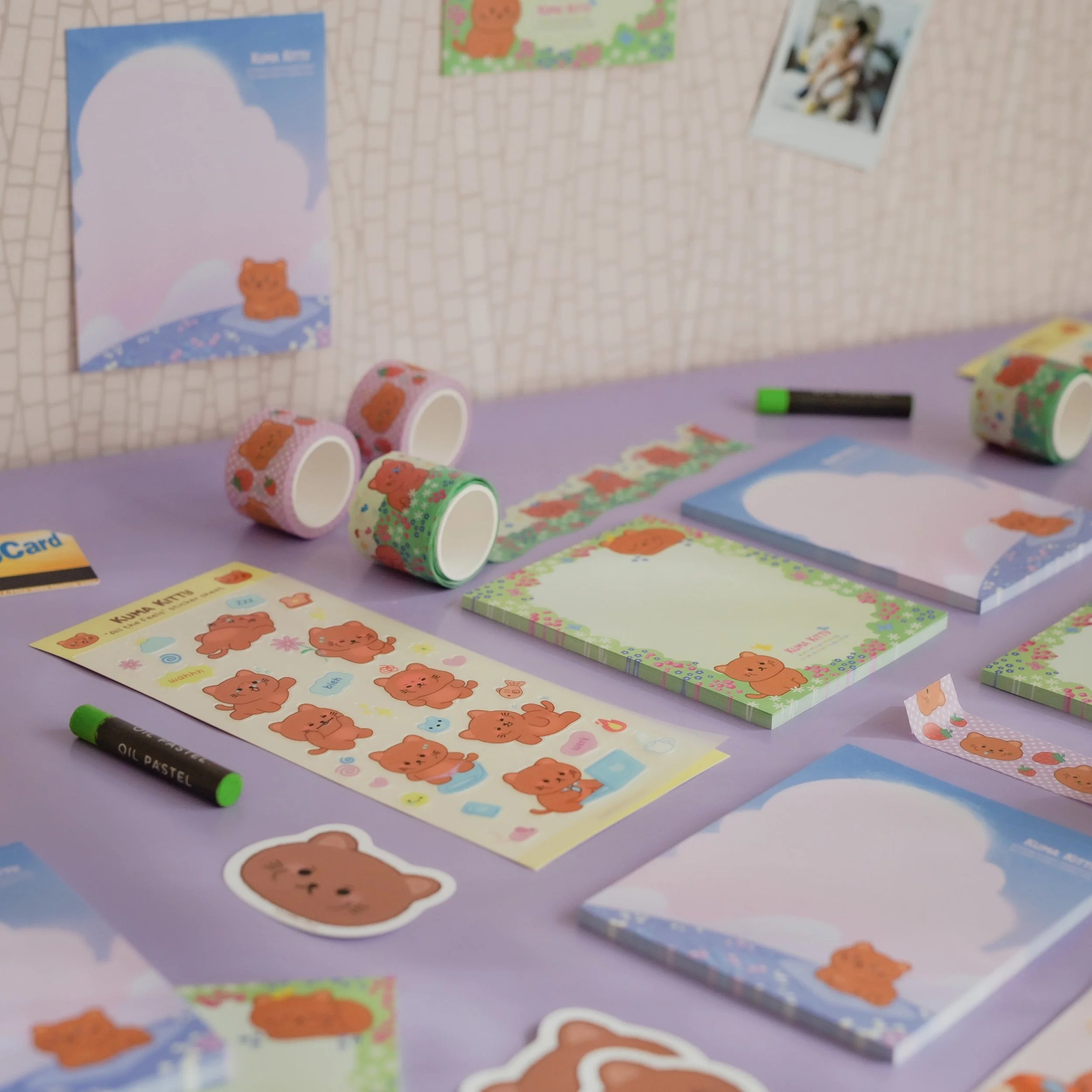 A collection of bear-themed stationery and decorations on a purple table, including stickers, washi tapes, notebooks, and a black marker, all with cute bear illustrations in pastel colors.