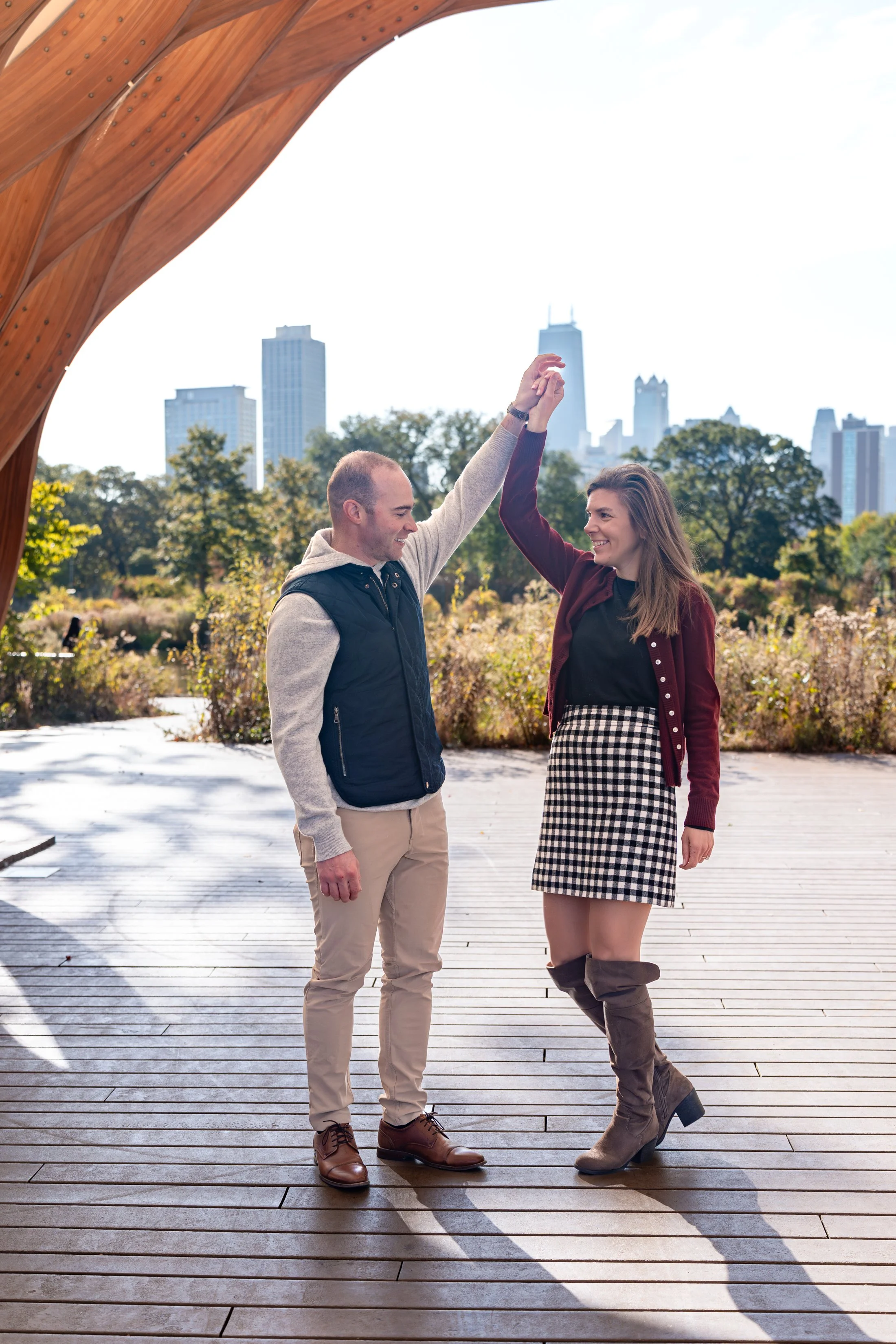 A couple dancing in an outdoor park with city skyscrapers in the background.