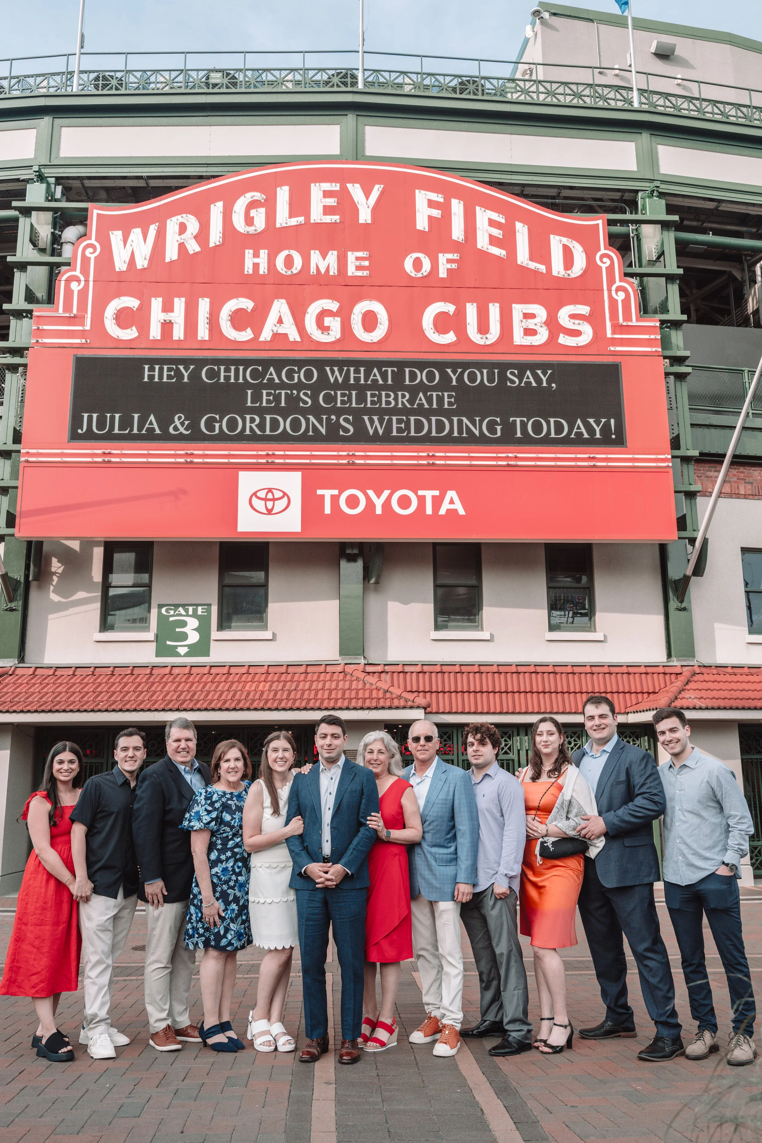 A group of people standing in front of Wrigley Field, home of the Chicago Cubs, during a celebration for Julia and Gordon's wedding.