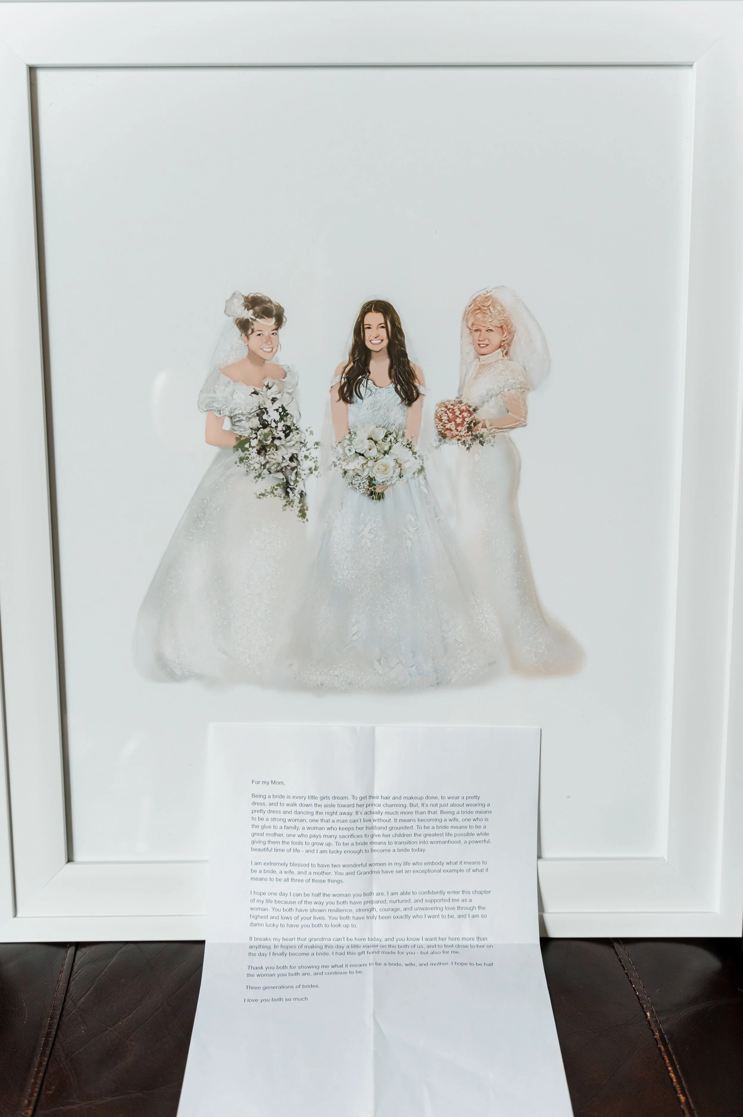 A framed wedding photo featuring three women in wedding dresses, holding bouquets, with a letter displayed below the frame.