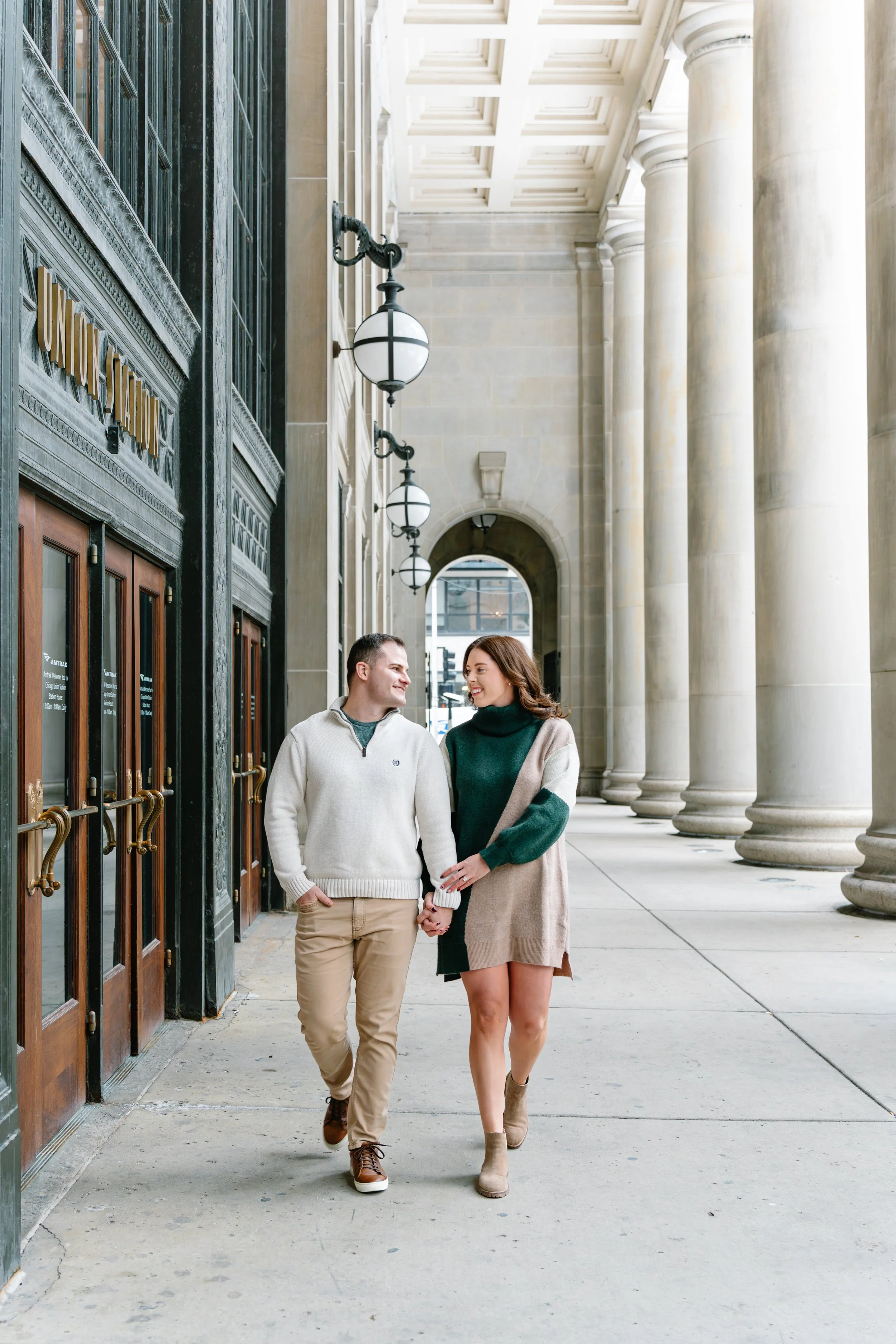 A couple walking by the U.S. Supreme Court building holding hands and smiling at each other.