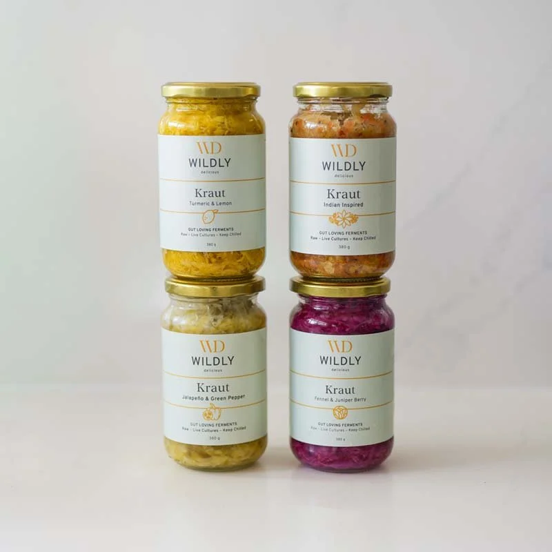 Four jars of wild fermented vegetables labeled with different flavors, including turmeric & lemon, Indian inspired, jalapeño & green pepper, and fennel & juniper berry, arranged in a 2x2 grid against a plain background.