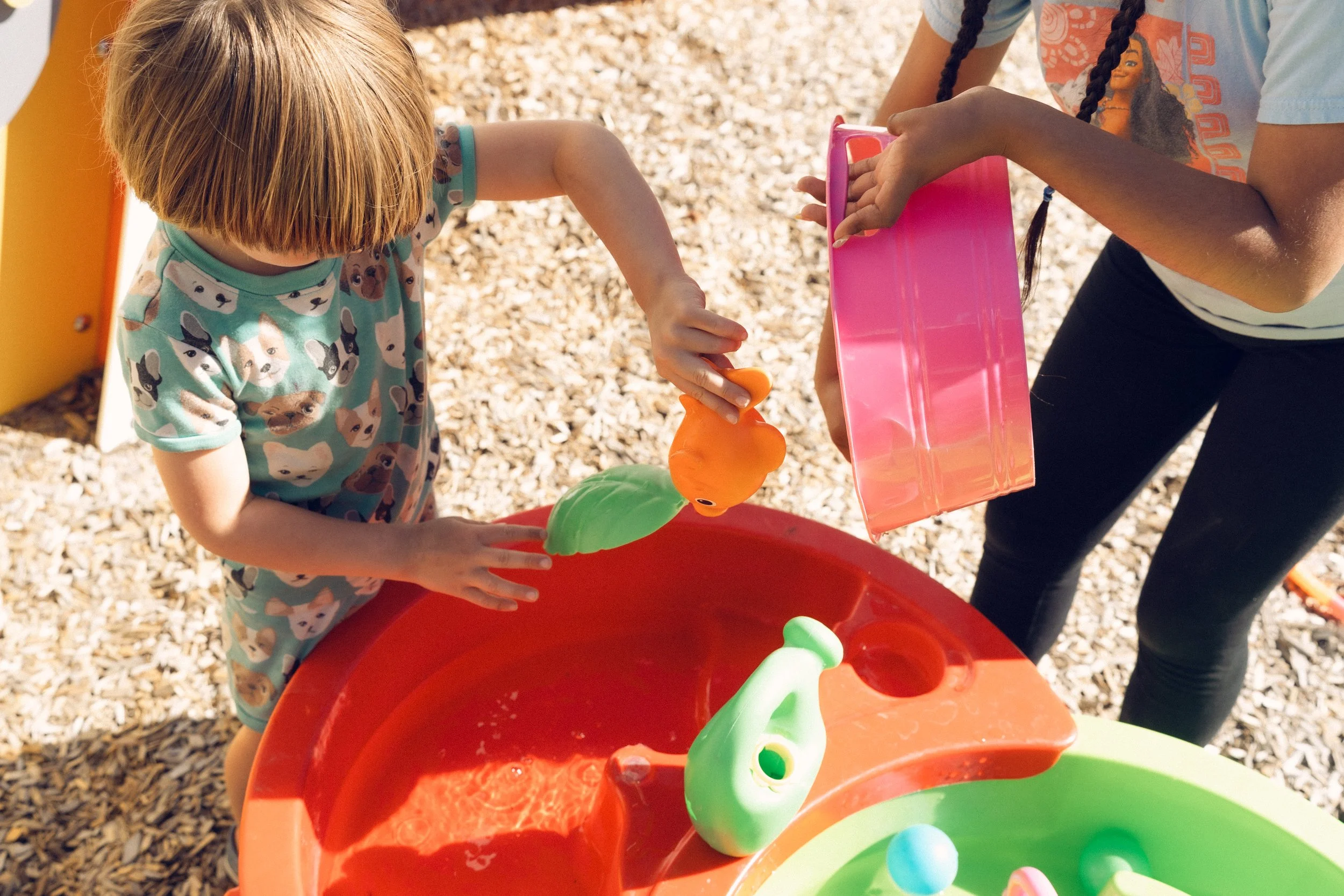 Two children playing with colorful slime or putty at an outdoor playground.