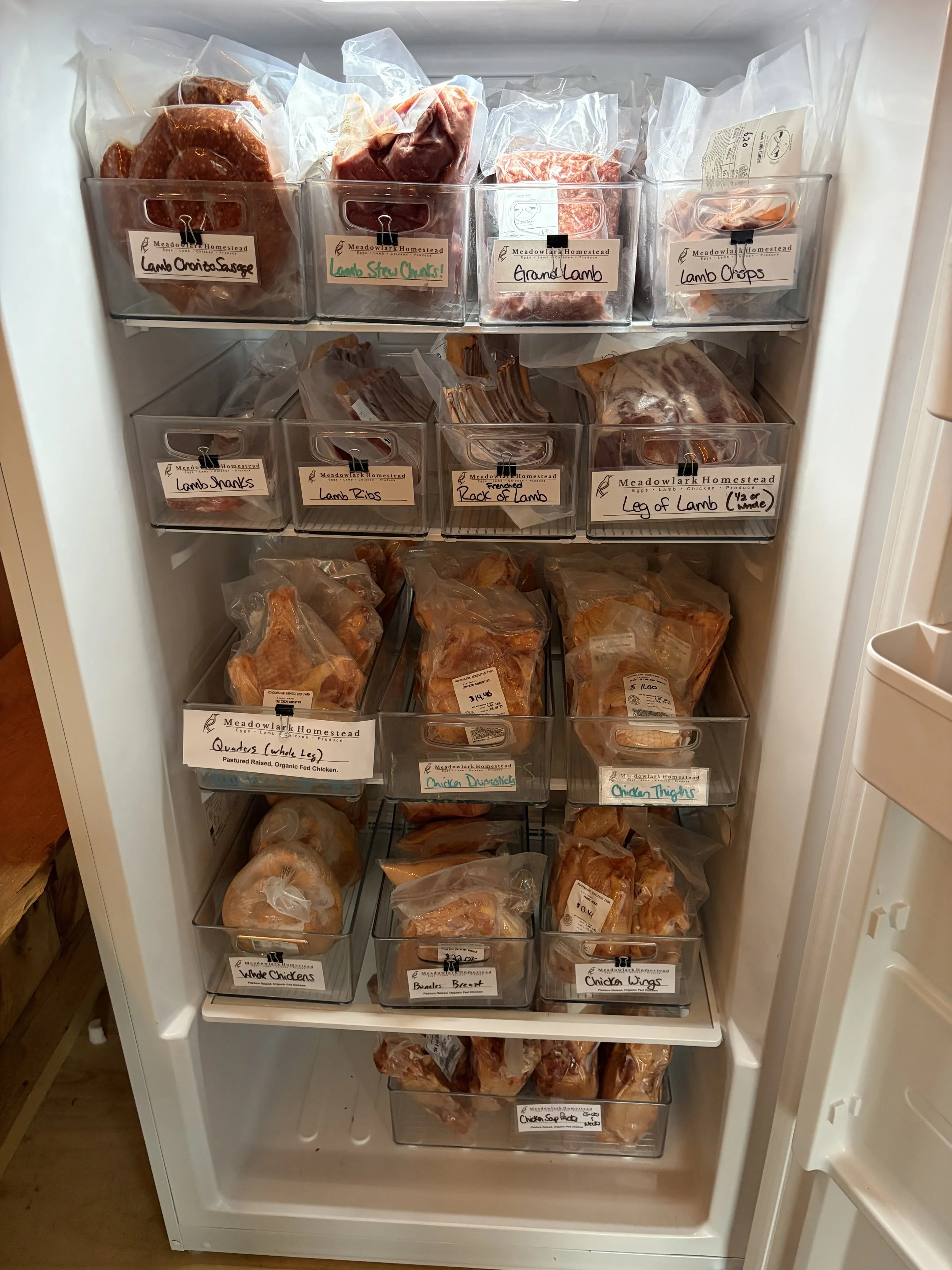 A freezer filled with packaged meats and poultry, including lamb, chicken, and brisket, each labeled with handwritten tags.
