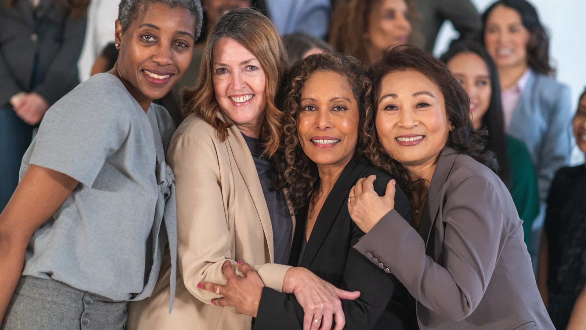 Group of diverse women smiling and embracing at a social gathering.
