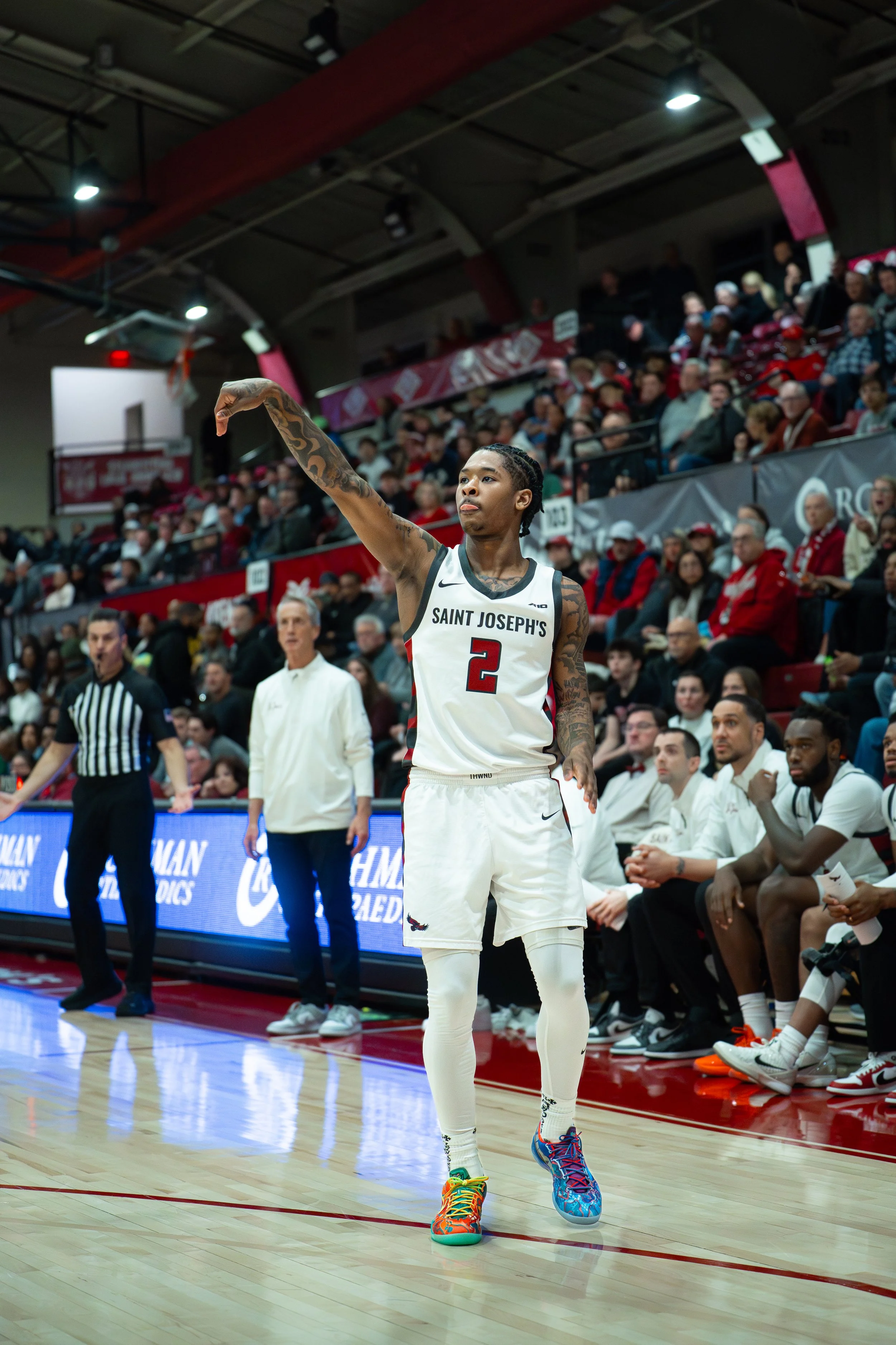 A basketball player from Saint Joseph's wearing a white jersey with the number 2, preparing to shoot during a game in a packed indoor arena.
