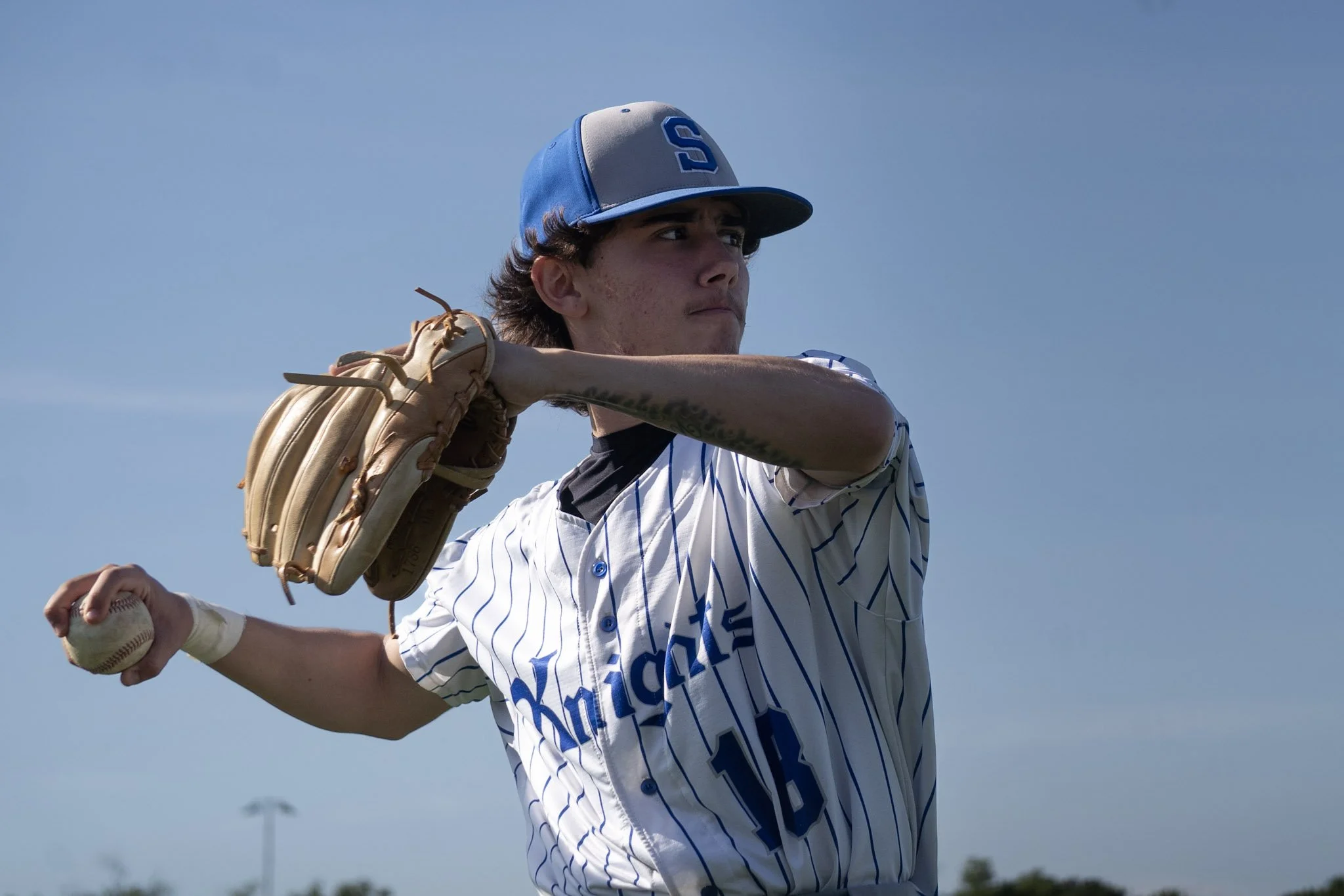 A young male baseball pitcher in uniform preparing to throw a ball during a game.
