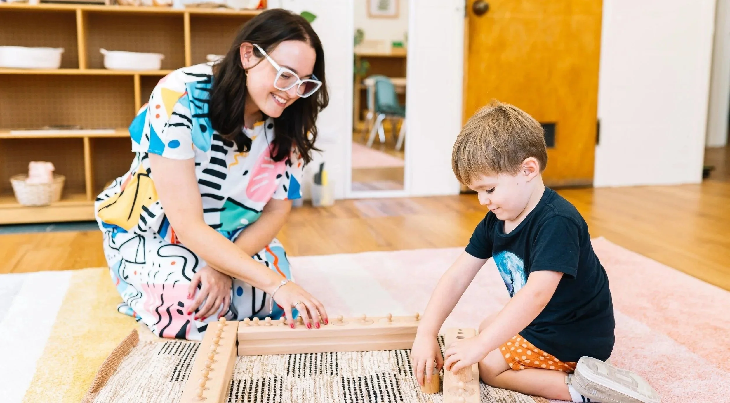 A woman and a young boy playing a game on a wooden board in a room with wooden floors and shelves.
