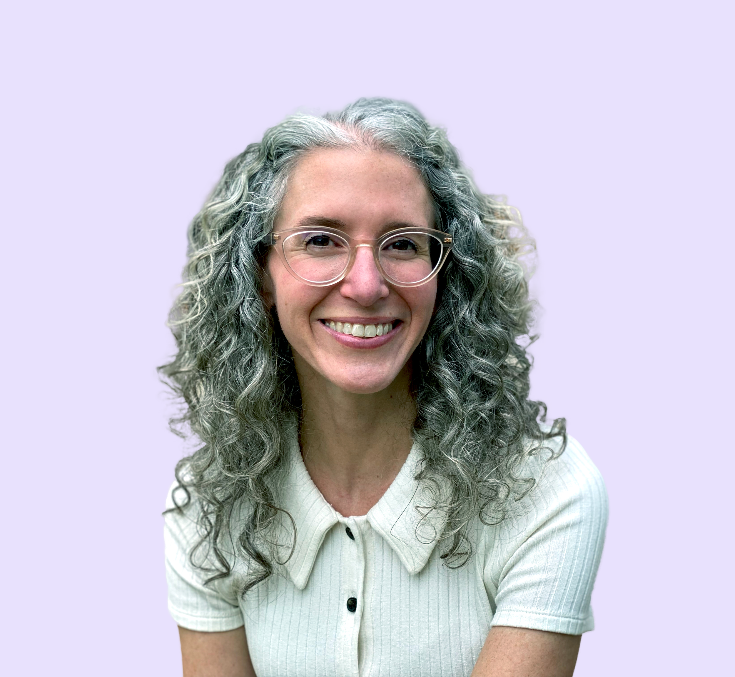 Photo of author Marisa Ramel, a woman with curly gray hair, wearing glasses and a light-colored collared shirt, smiling against a light purple background.