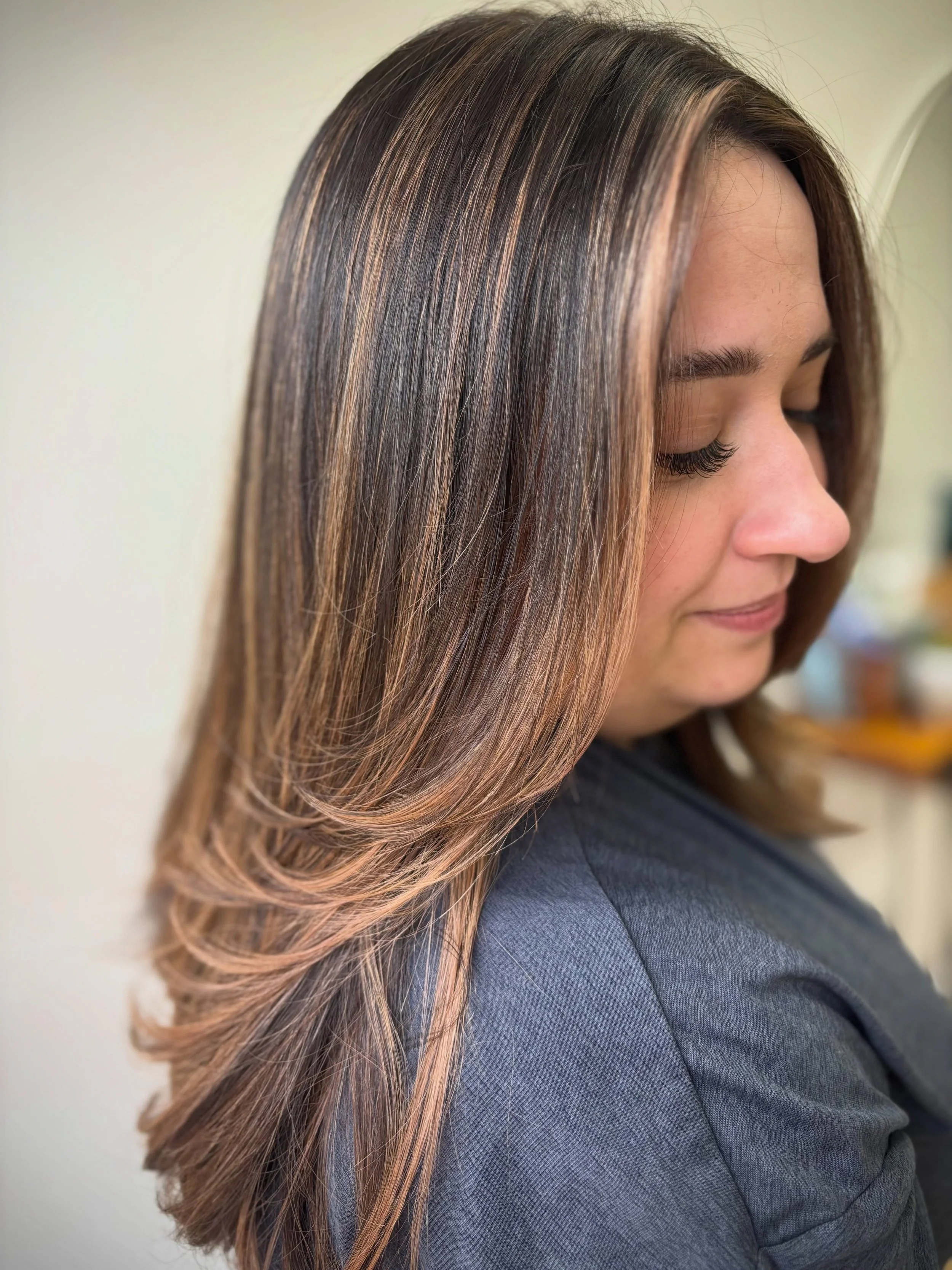 Dimensional brunette going brighter for summer. This look is designed to enhance your natural hair colour with seamless, low-maintenance details in all the right places. Finished with a layered haircut to add movement that flows perfectly with your c