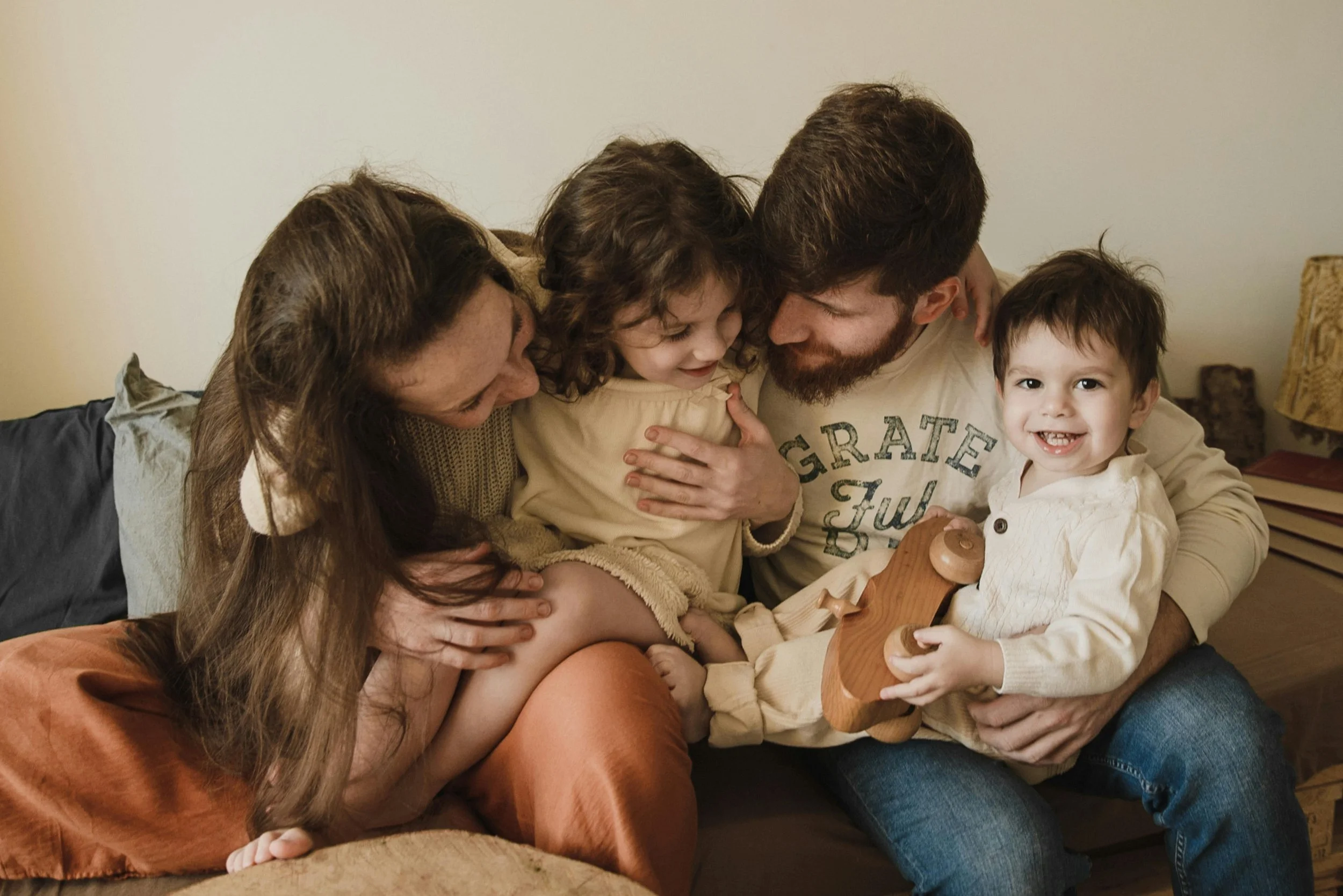 Family gathered on a couch, laughing and hugging each other.