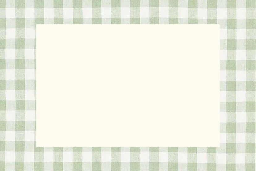 Blank white rectangular piece of paper on a green and white checkered tablecloth.