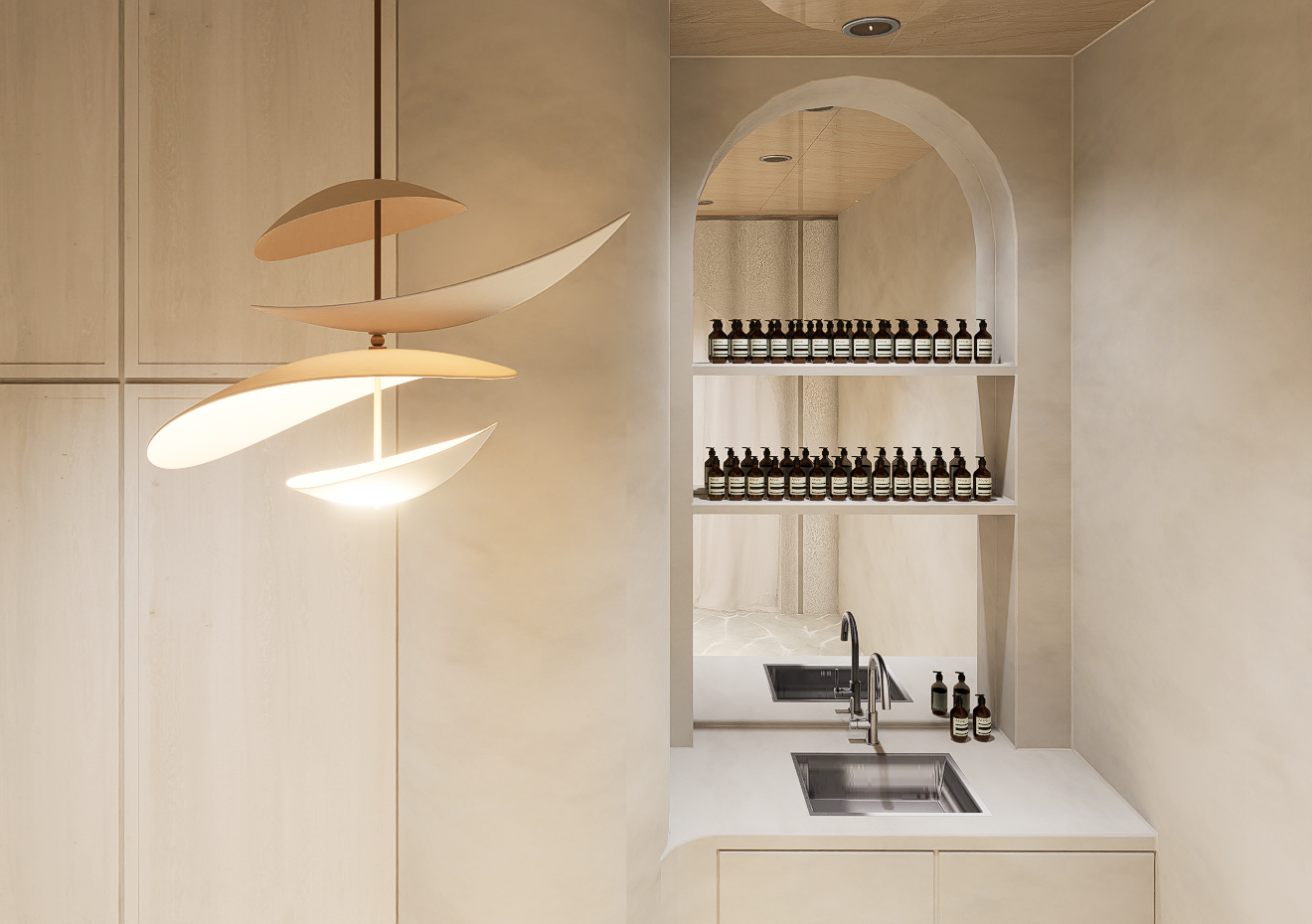 A modern kitchen with a beige and neutral color palette featuring a unique ceiling light fixture, a mini-shelf with rows of small bottles, a small sink, and an arched shelf opening.
