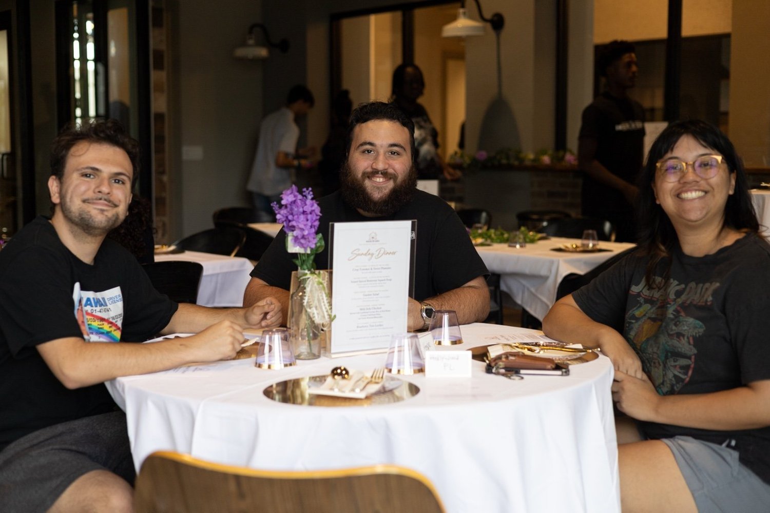 Guests smiling together around a table at The House of Eden’s first Sunday Dinner.