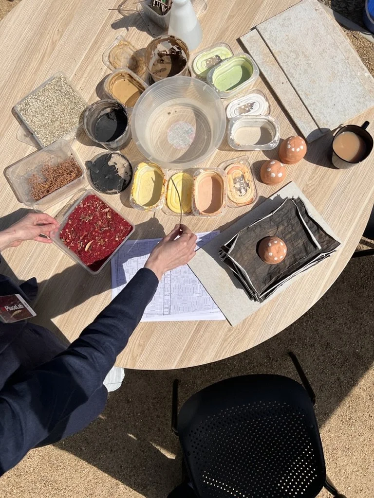 A birds eye view of a table with clay paint and stick brushes.