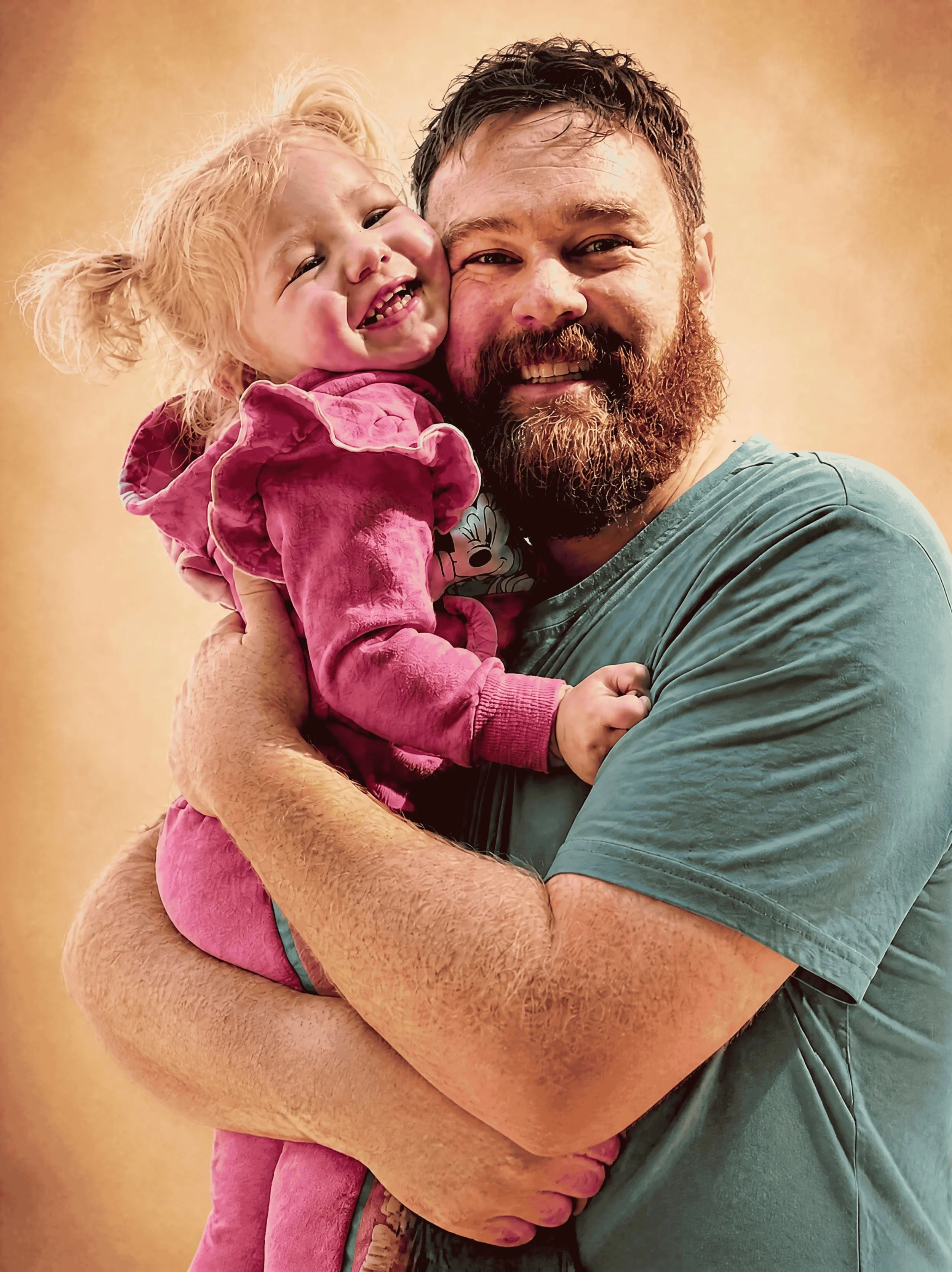 A man with a beard holding a little girl with curly hair, both smiling and looking happy.