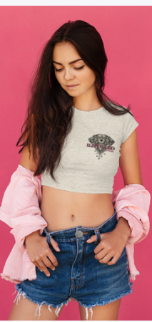 Young woman with long dark hair, wearing a crop top, denim shorts, and a pink jacket hanging off her shoulders, standing against a pink background.