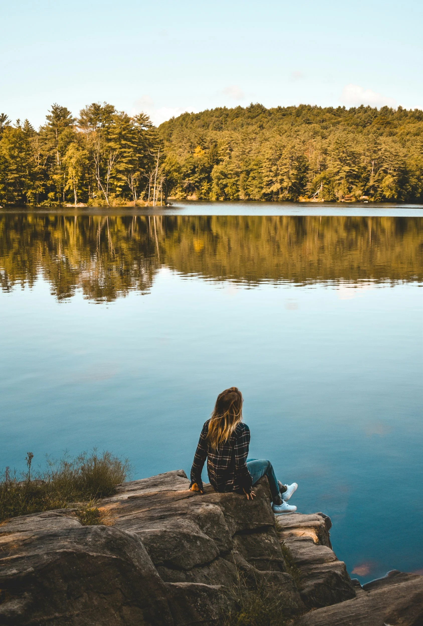 Woman relaxing at the side of a lake and looking over the lake.