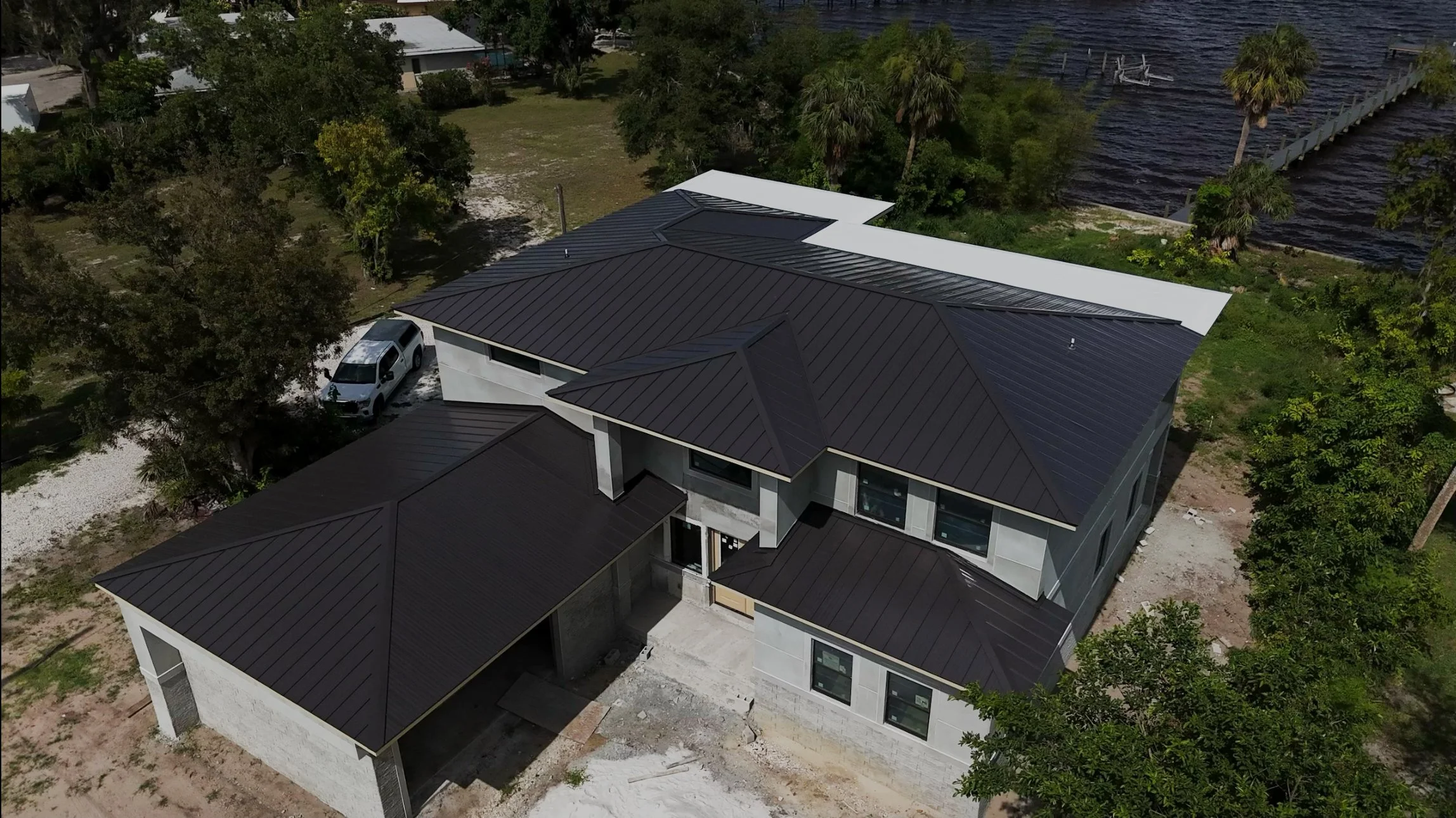 Aerial view of a modern house with dark metal roofs that is newly installed on a new construction home.