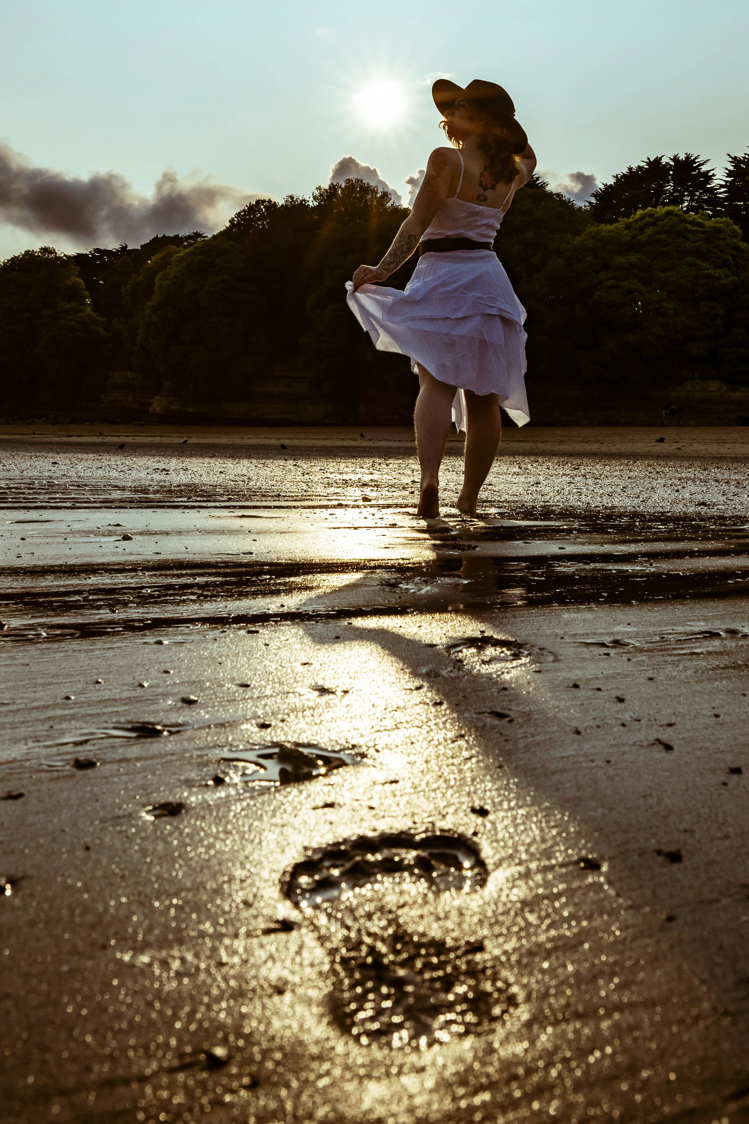 Bethanie Model walking into the sunset on a sandy beach leaving footprints