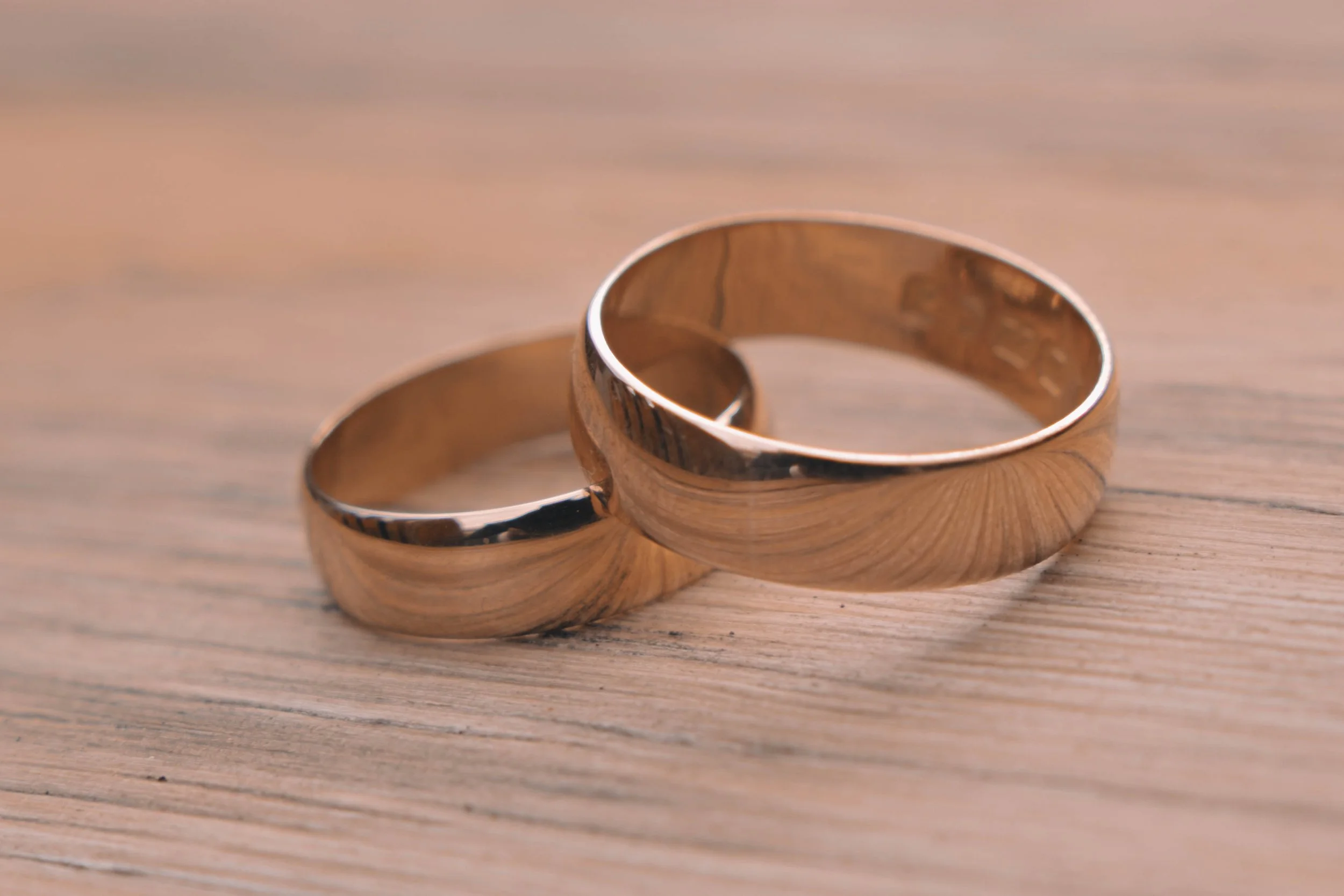 Two gold wedding bands placed on a wooden surface.