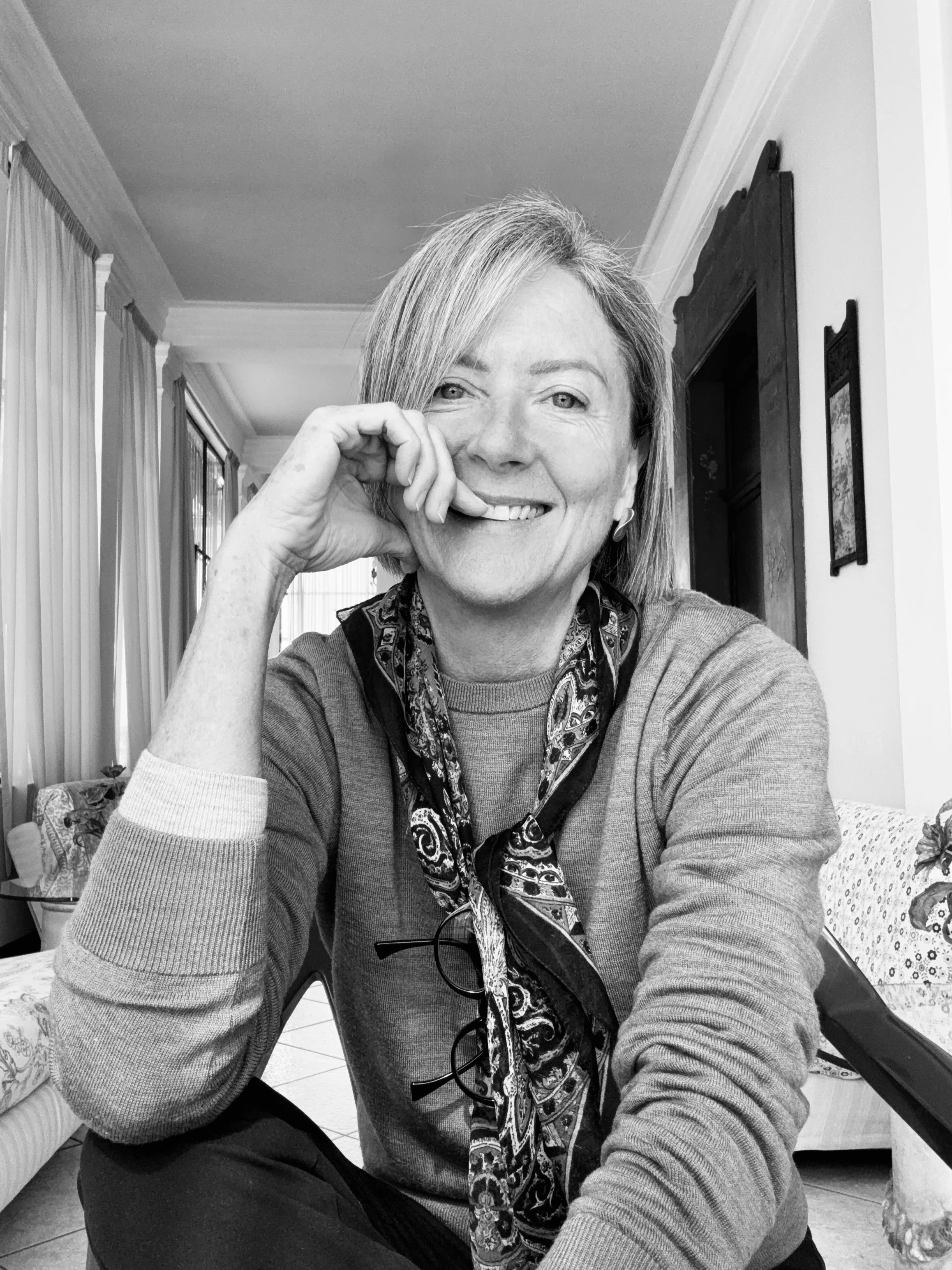 Black and white portrait of Australian artist KT Doyle smiling in a relaxed interior setting