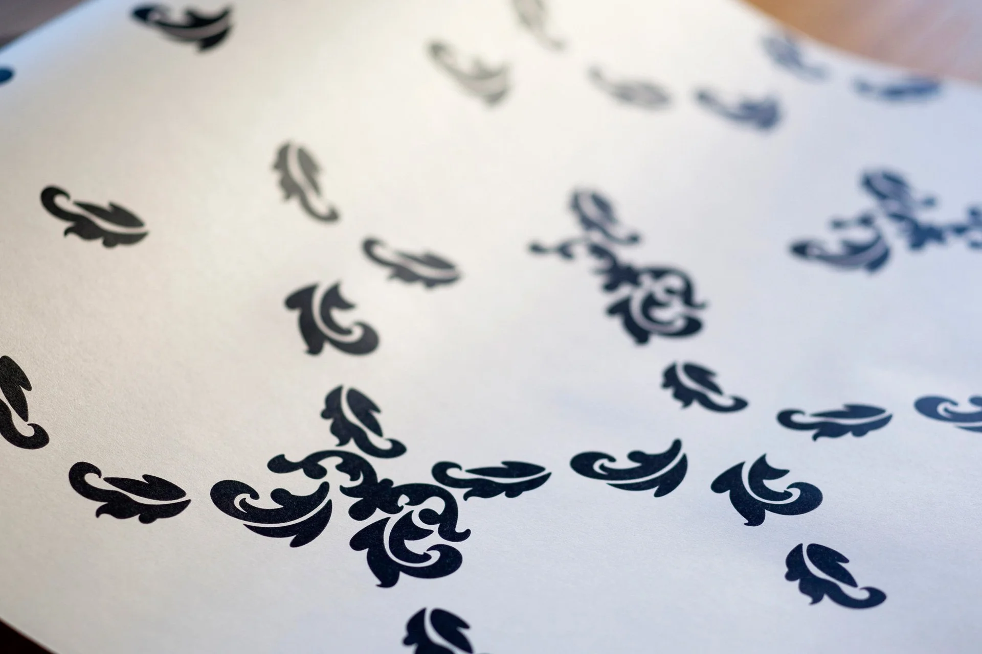 Falling Leaves wallpaper by KT Doyle, showing scattered black leaf motifs forming a loose repeating pattern on white