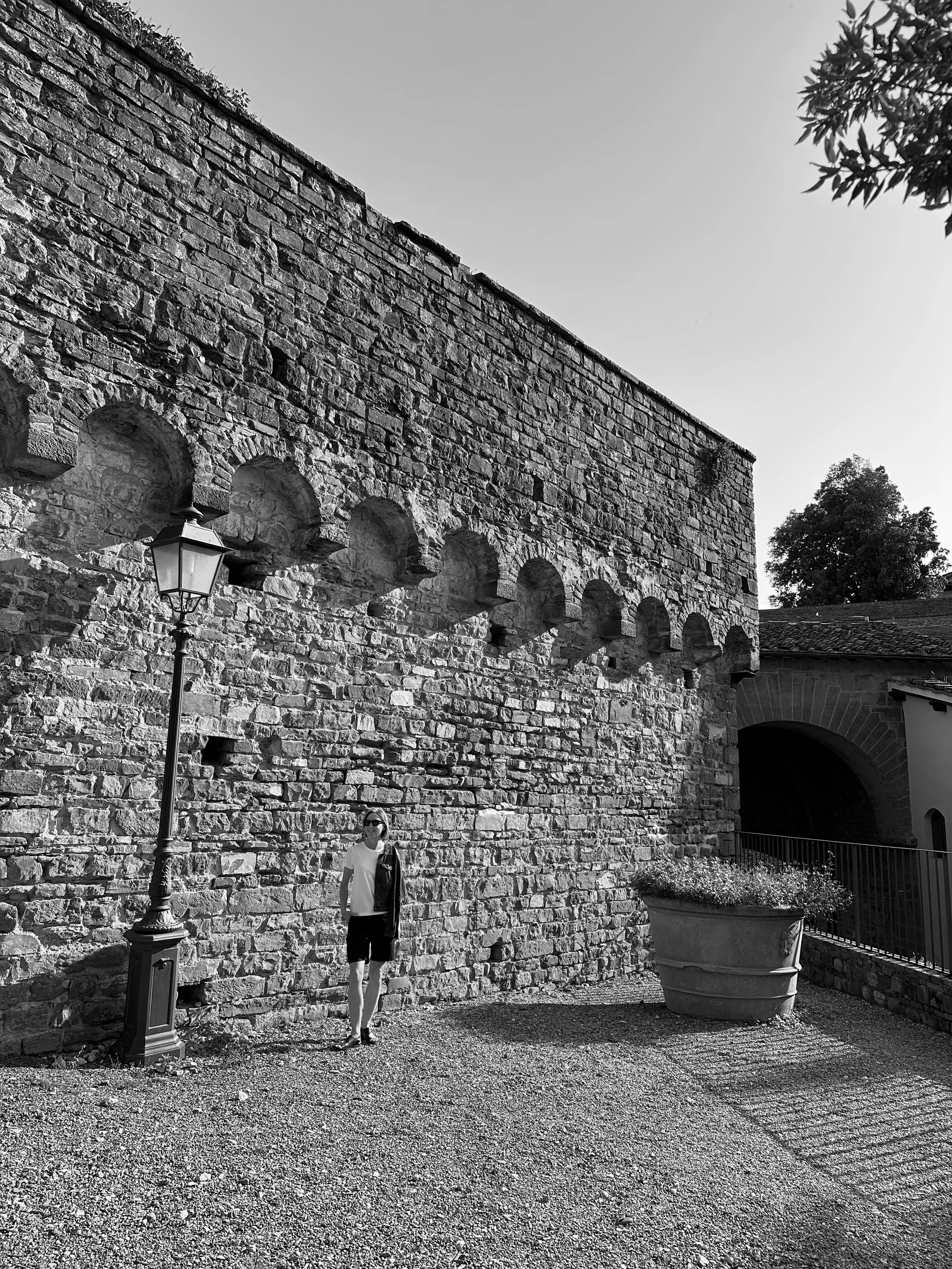 Australian artist KT Doyle standing beside a historic stone wall in Florence, Italy