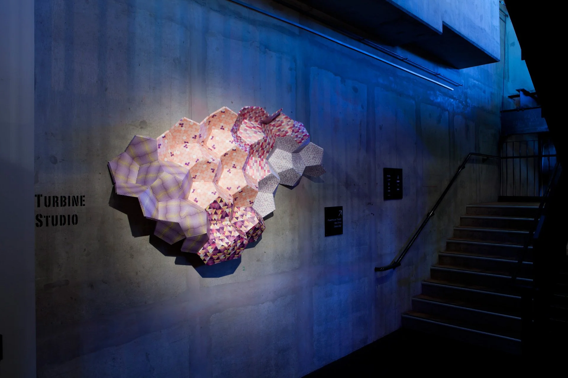 Stitched Together by KT Doyle and Robert Davidson installed at Brisbane Powerhouse, with patterned sculptural forms illuminated against the concrete wall