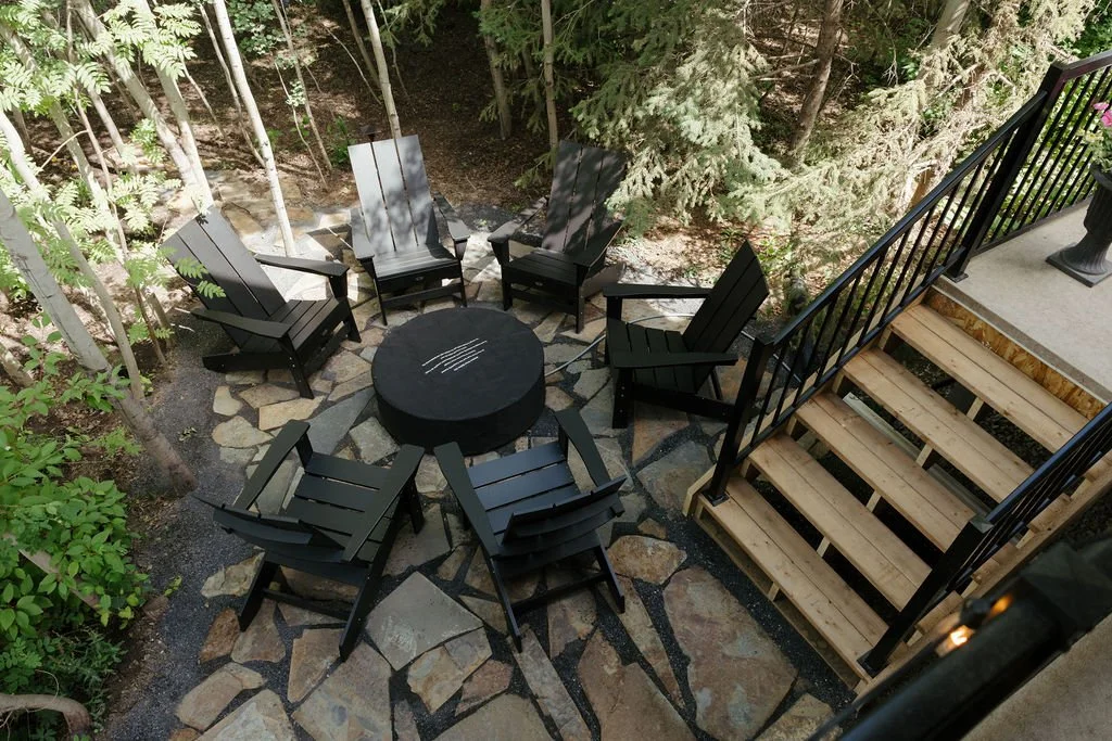 Photo of mountain range with reddish-brown peaks and snow patches, and a green grassy foreground, under a clear blue sky.