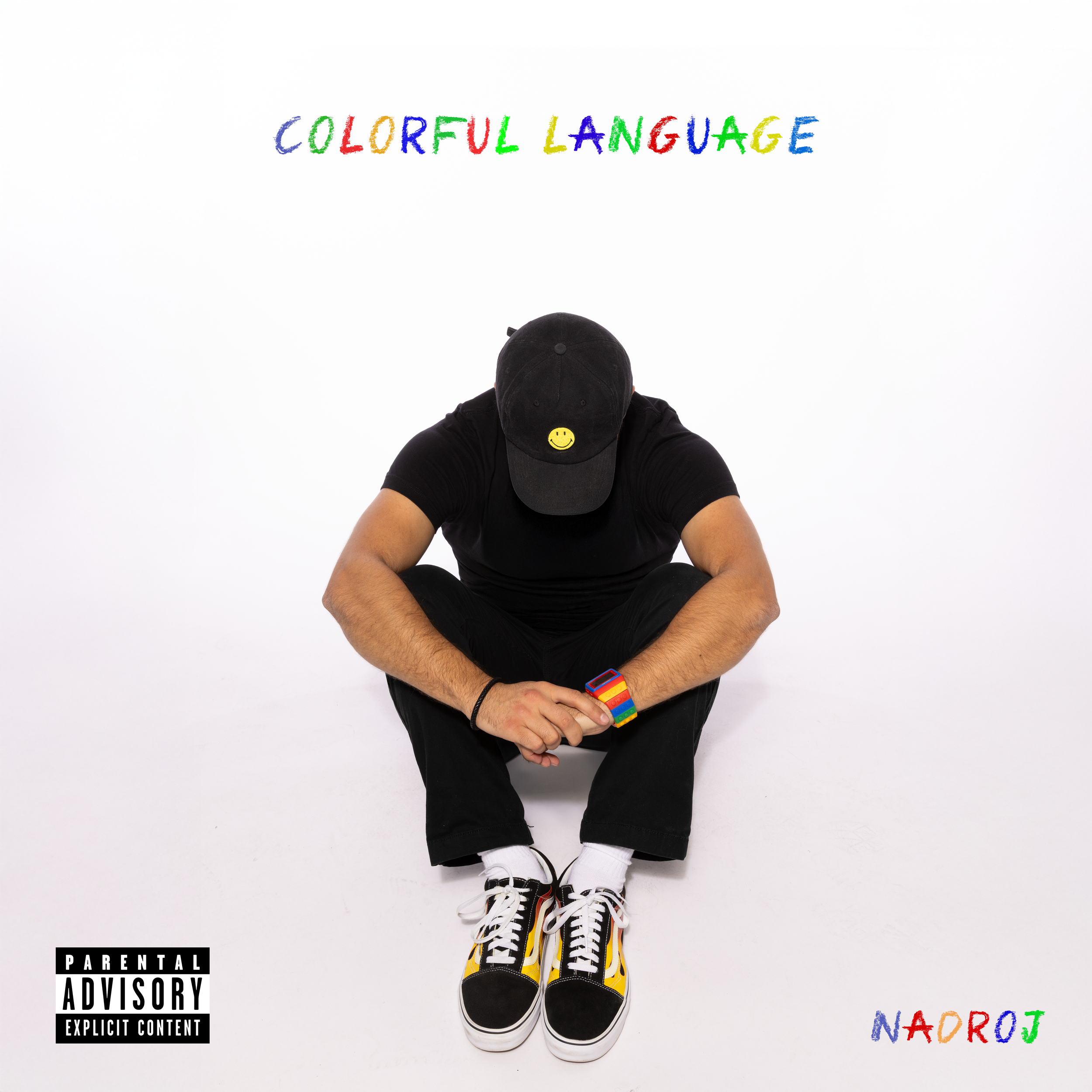 A person wearing a black cap with a yellow smiley face, a black T-shirt, black pants, and colorful sneakers, sitting cross-legged on a white floor against a white background with colorful text that reads 'Colorful Language' at the top and 'Nadroj' at the bottom right. There is a parental advisory label in the bottom left corner.