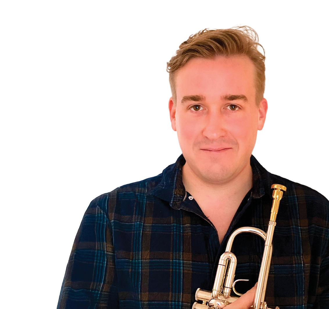 A young man with short, light brown hair, wearing a dark plaid shirt, holding a trumpet, and standing against a dark background. Tom Walsh