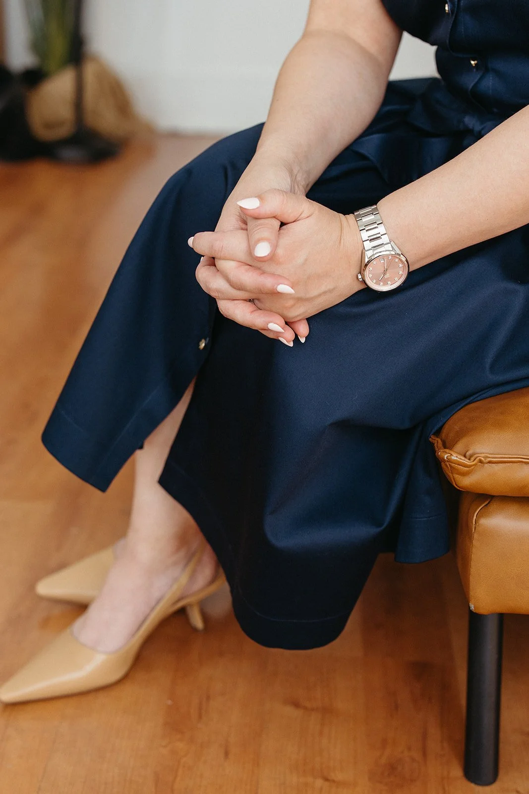 Clasping hands on a navy blue dress during a session with Brea, CA anxiety therapist Jaclyn Staubach, LCSW.