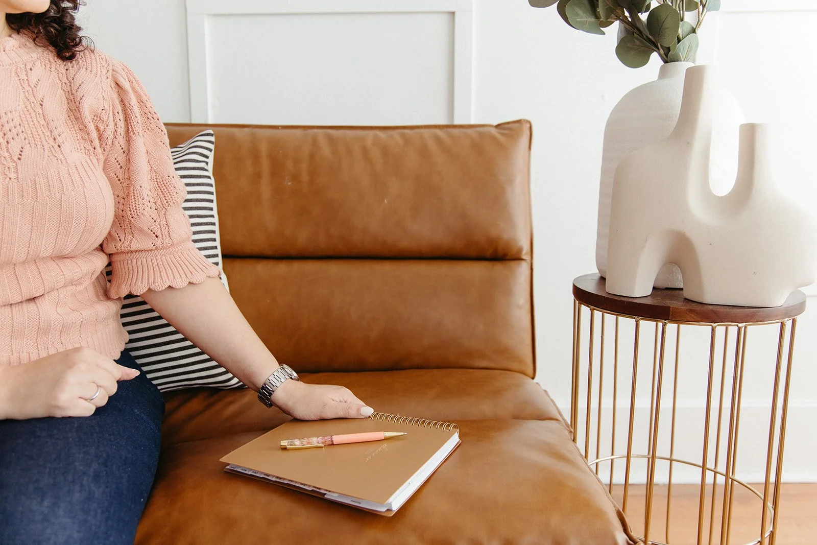 Hand clasping a brown notebook on a leather couch while scheduling an anxiety therapy session in Brea, CA.