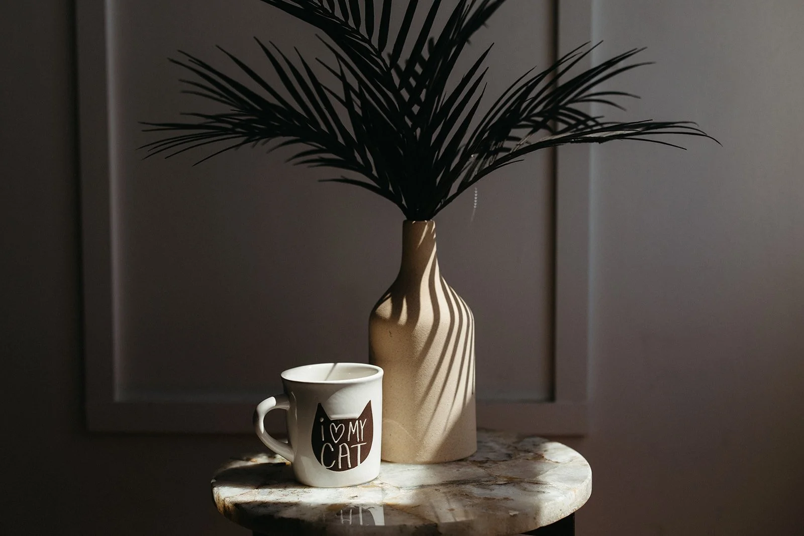 a mug next to vase with palm leaves