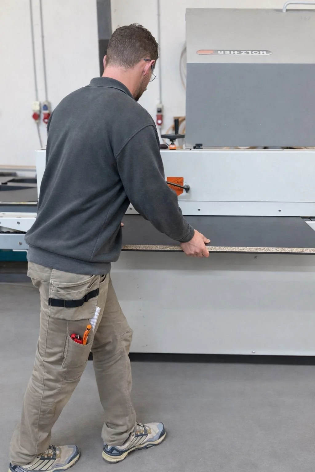 Ein Mann arbeitet in einer Fabrik oder Werkstatt mit einer großen Maschine.