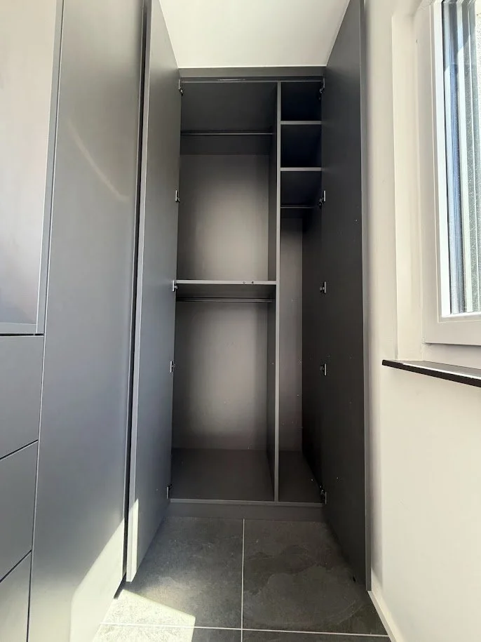 Leeres graues Kleiderschrank in einem Raum neben einem Fenster.