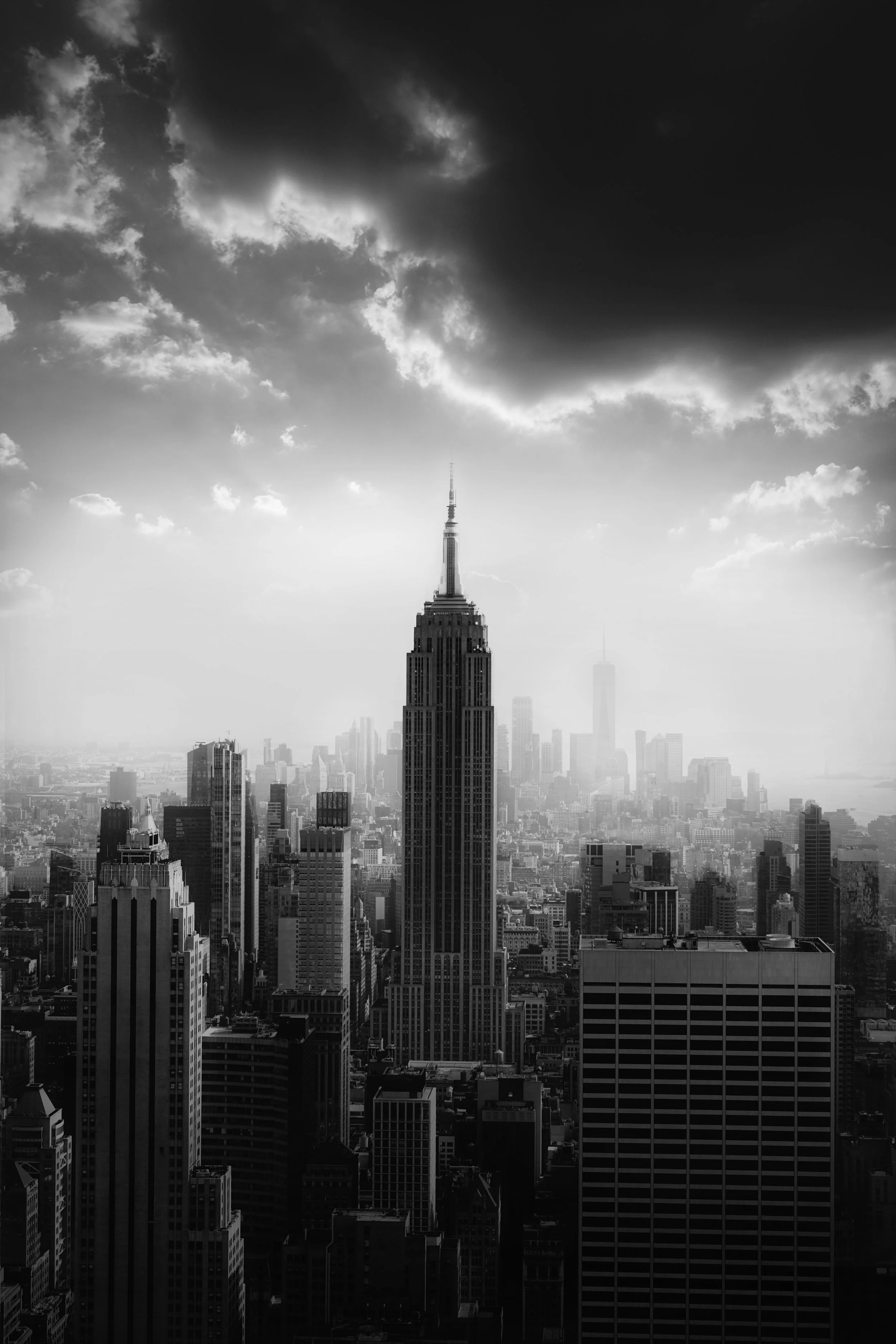 Black and white photo of the Empire State Building in New York City with dark clouds overhead.