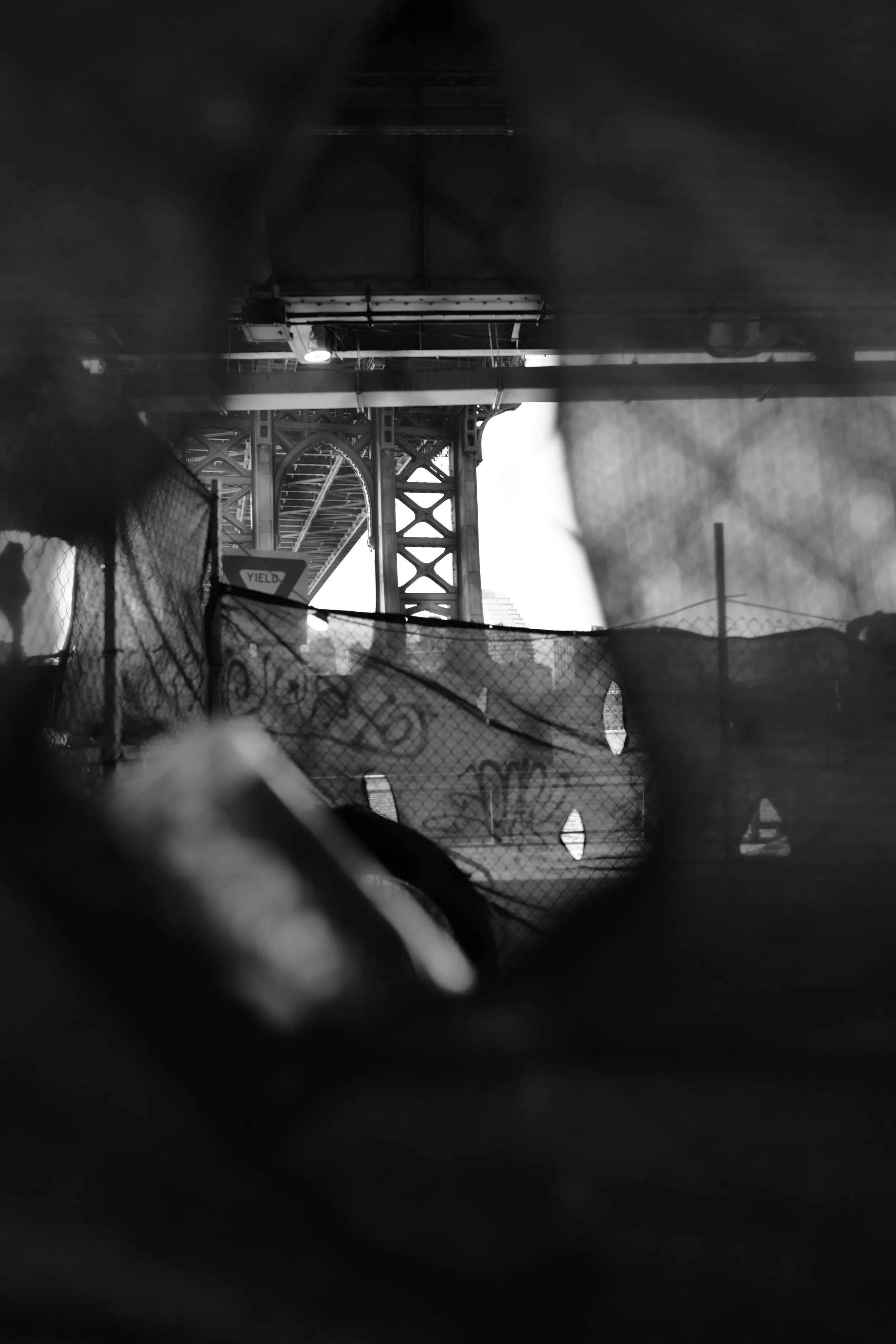 View of a bridge structure taken from underneath, with fencing and debris in the foreground in black and white.