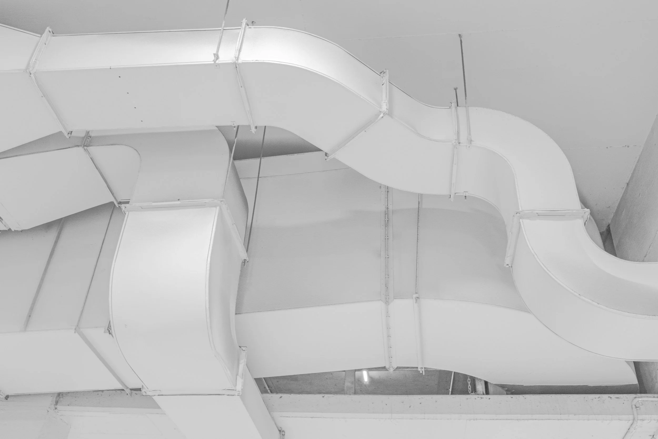 Black and white photo of large, curved ventilation ducts or air ducts on a ceiling.