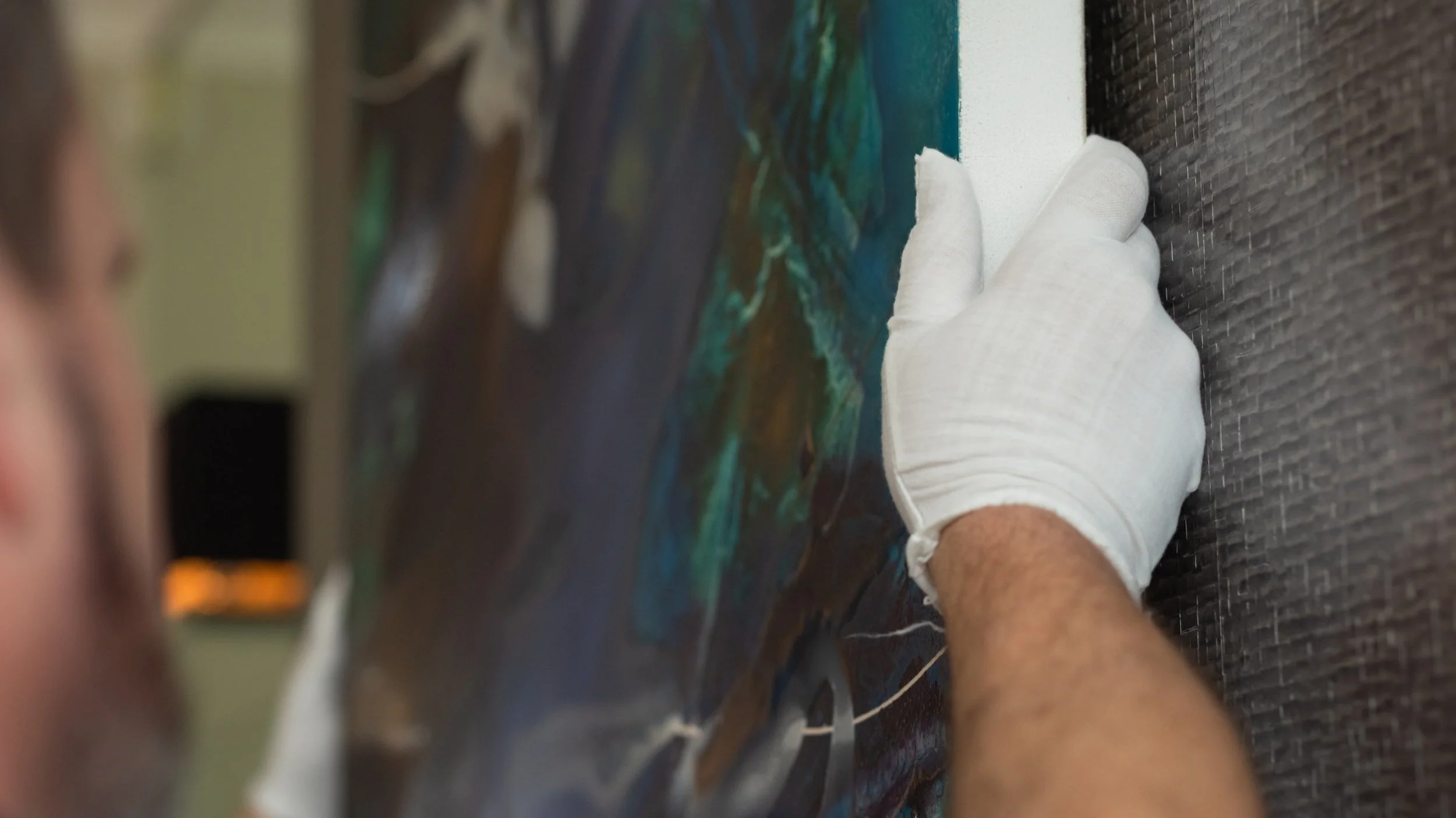 Fine art being hung on a wall with white gloves